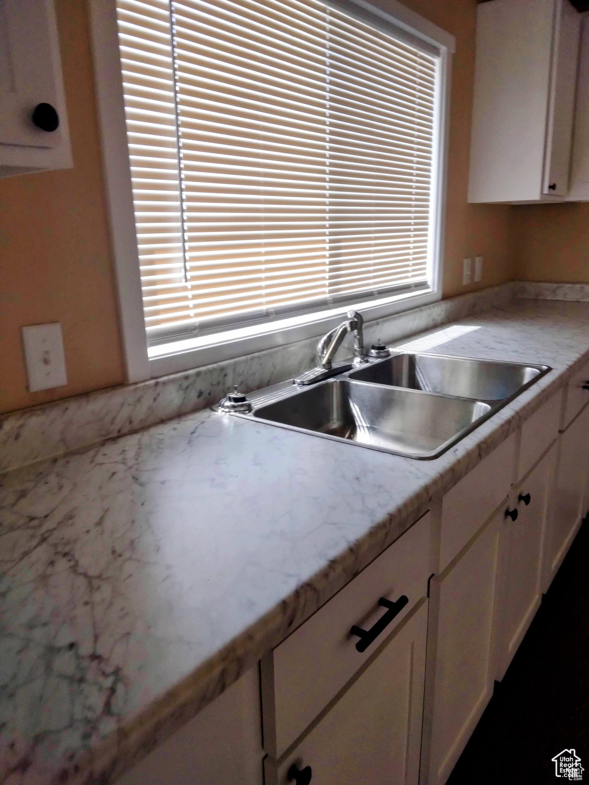 Kitchen with sink, white cabinets, and plenty of natural light