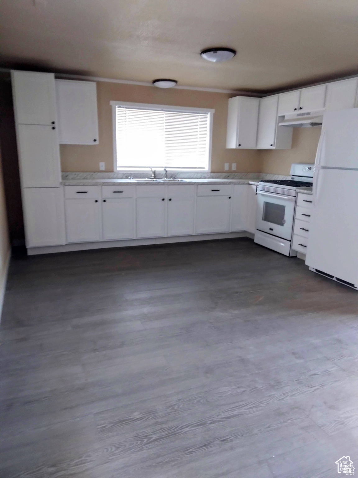 Kitchen featuring white appliances, white cabinetry, and sink