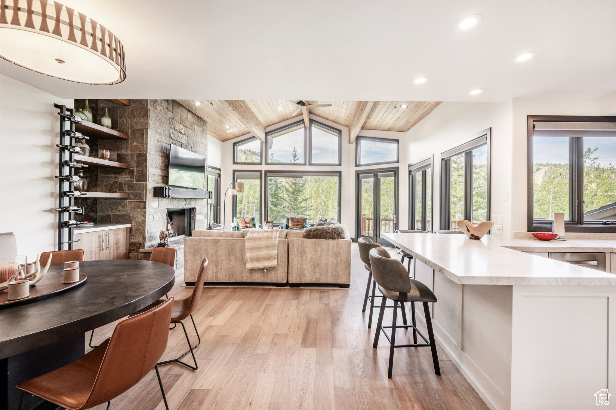 Dining area with vaulted ceiling with beams, light hardwood / wood-style flooring, a stone fireplace, and wood ceiling