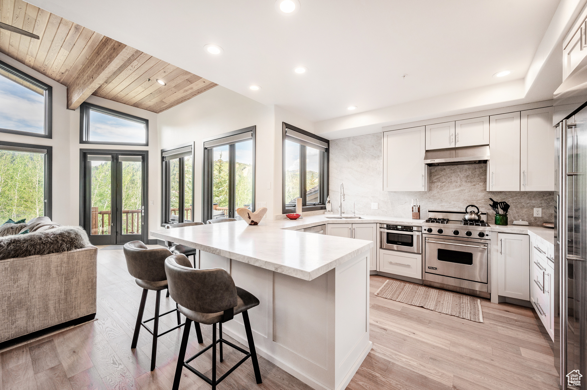 Kitchen featuring a kitchen breakfast bar, light wood-type flooring, wood ceiling, designer range, and sink