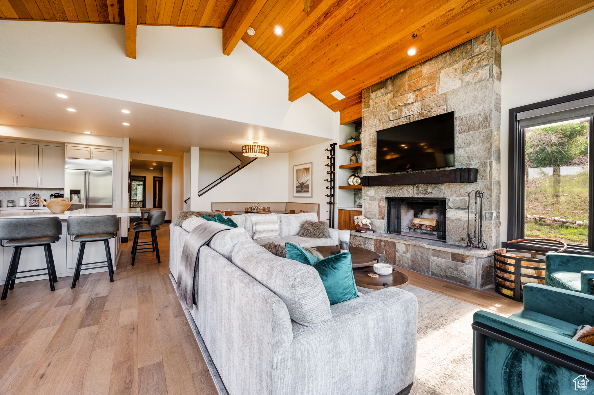 Living room with high vaulted ceiling, light hardwood / wood-style flooring, beamed ceiling, wooden ceiling, and a fireplace