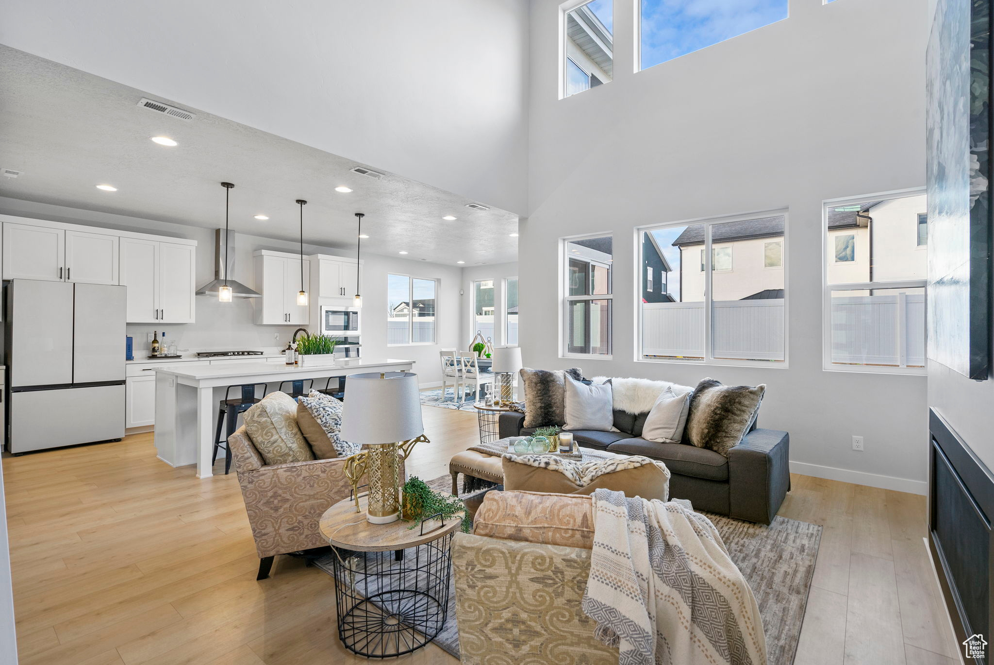 Living room with a wealth of natural light, a towering ceiling, and light hardwood / wood-style floors