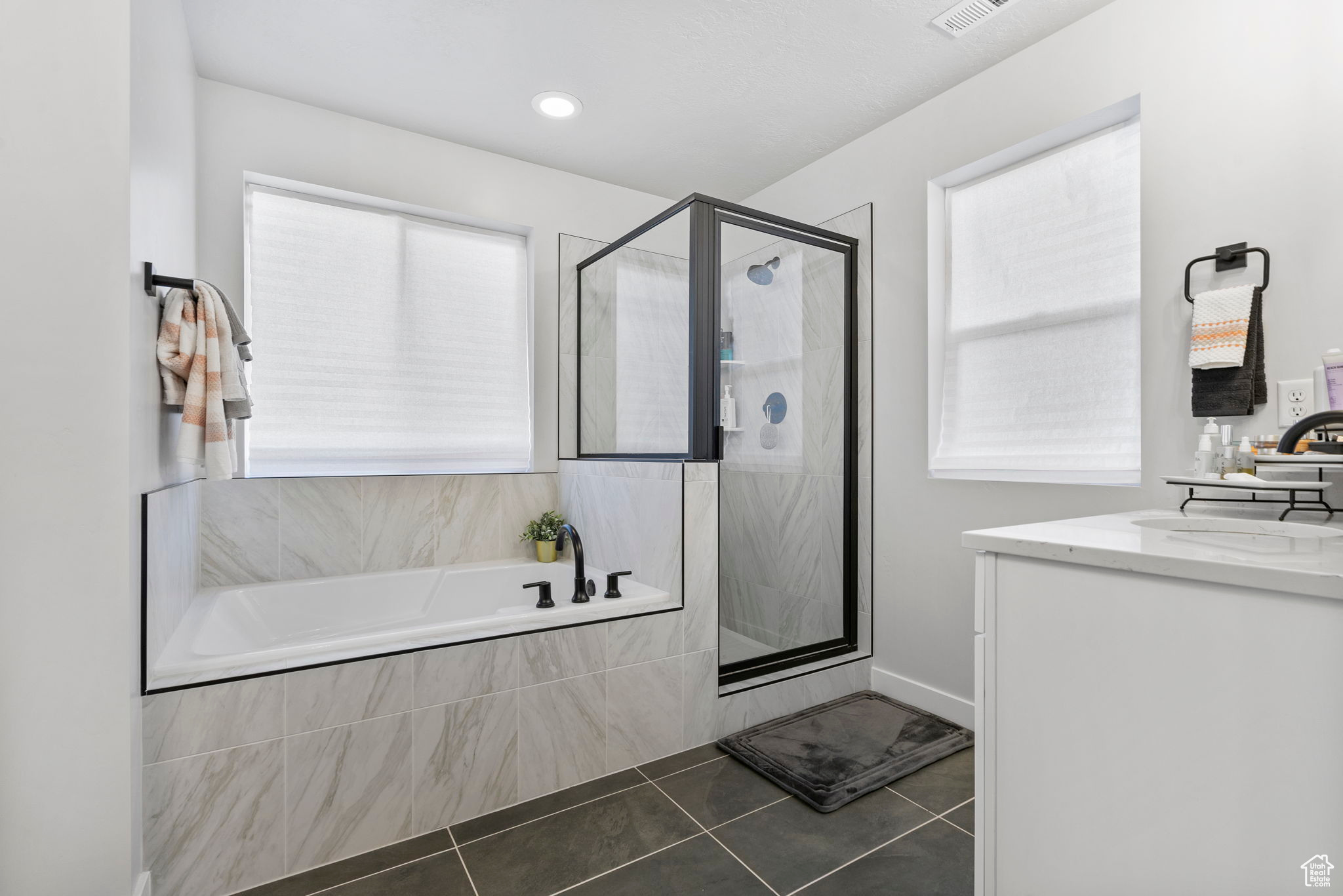 Bathroom with tile patterned flooring, vanity, and shower with separate bathtub