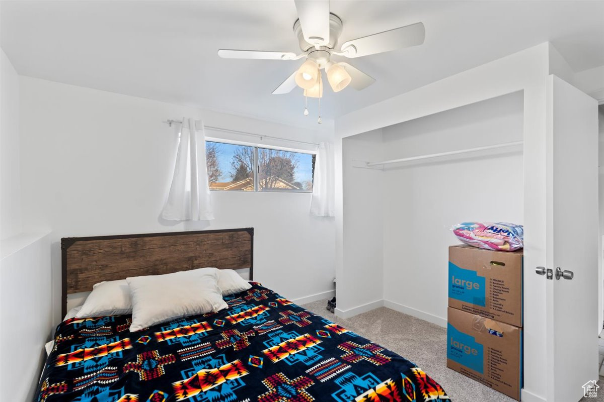 Carpeted basement bedroom with ceiling fan