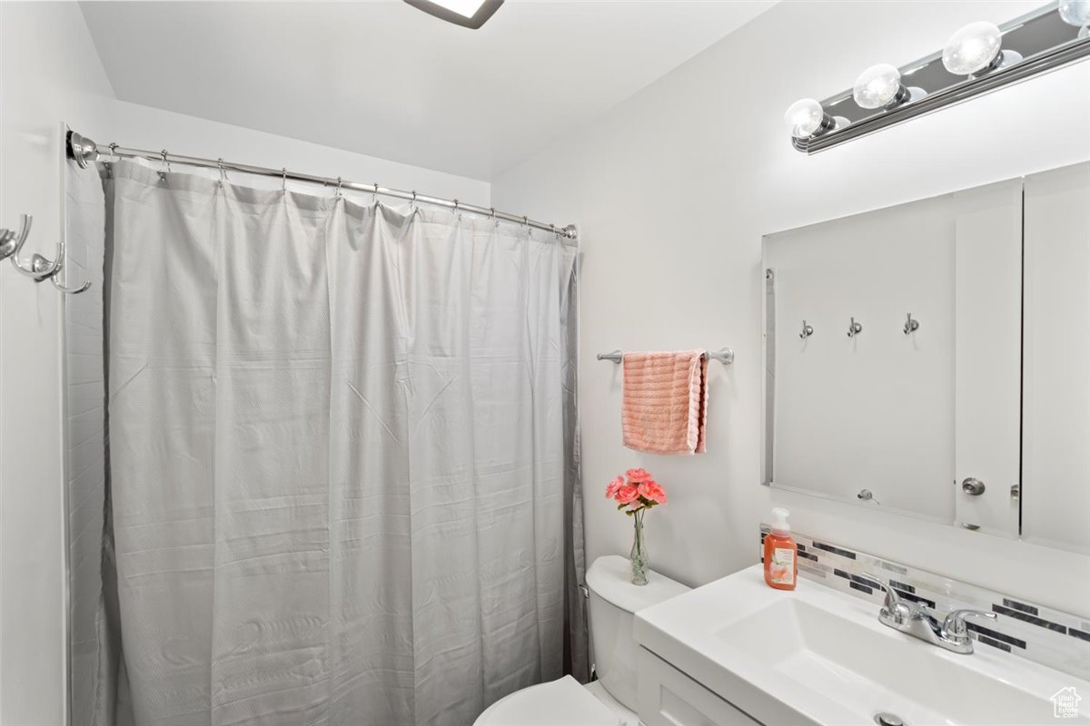 Remodeled upstairs bathroom featuring decorative backsplash, vanity, a shower, and toilet
