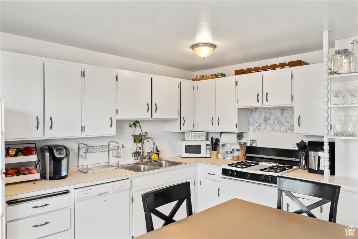 Kitchen with white cabinetry, sink, and white appliances