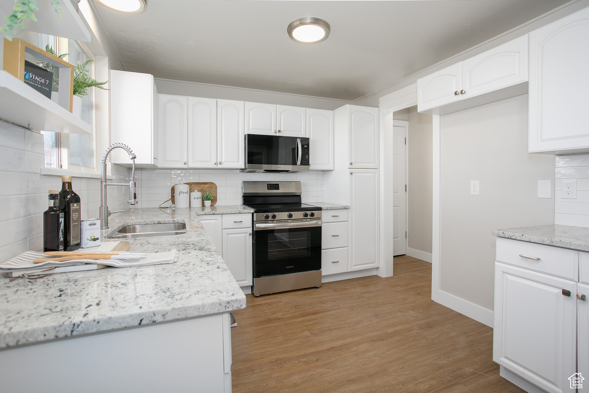 Kitchen with tasteful backsplash, white cabinetry, sink, and stainless steel appliances