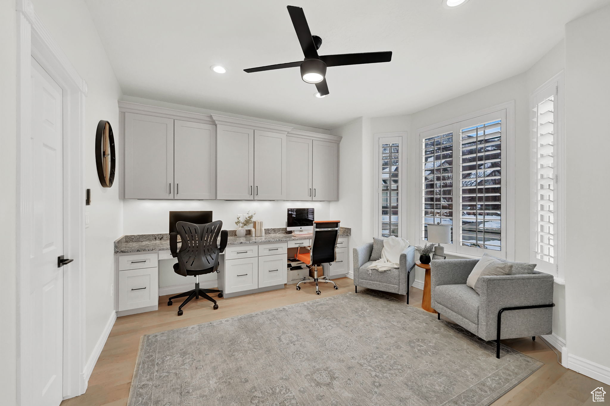 Office space featuring ceiling fan, built in desk, and light hardwood / wood-style flooring