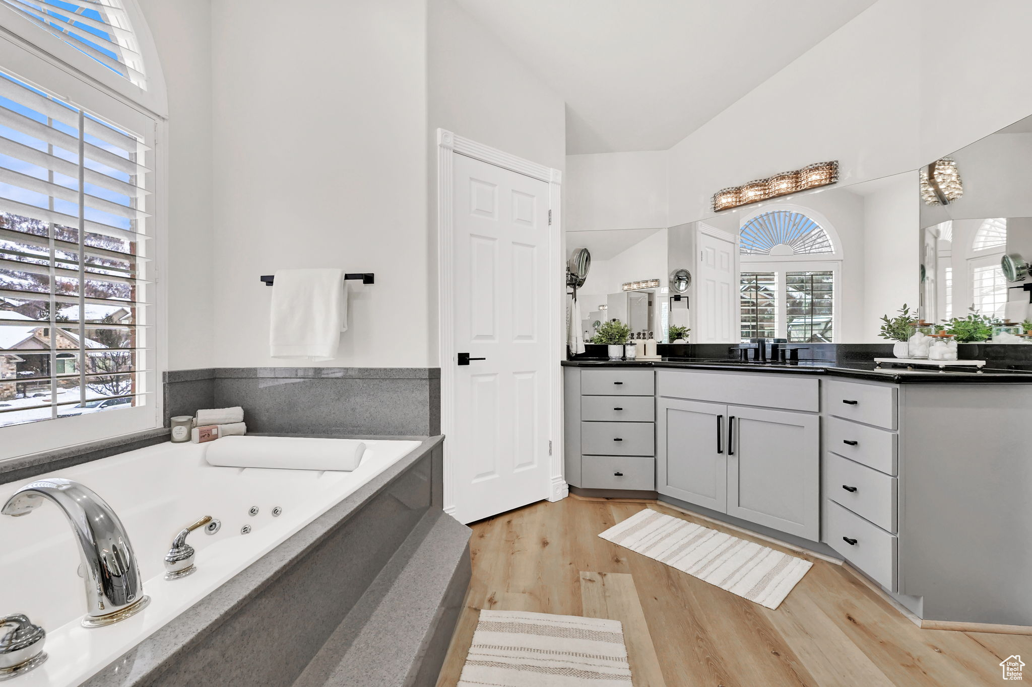 Bathroom with vanity, wood-type flooring, a tub, and vaulted ceiling