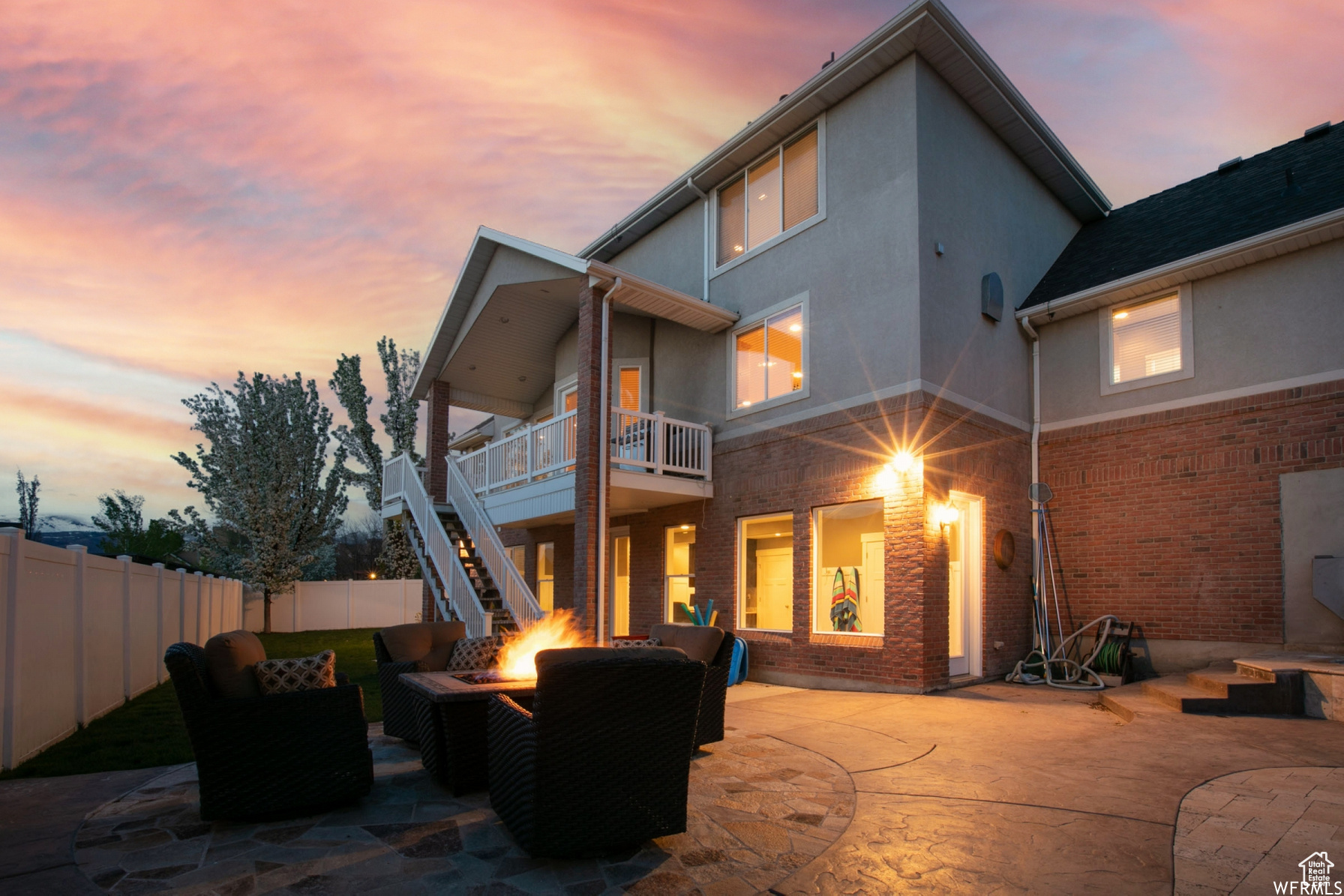 Back house at dusk with a covered deck and covered patio and an outdoor gas fire pit