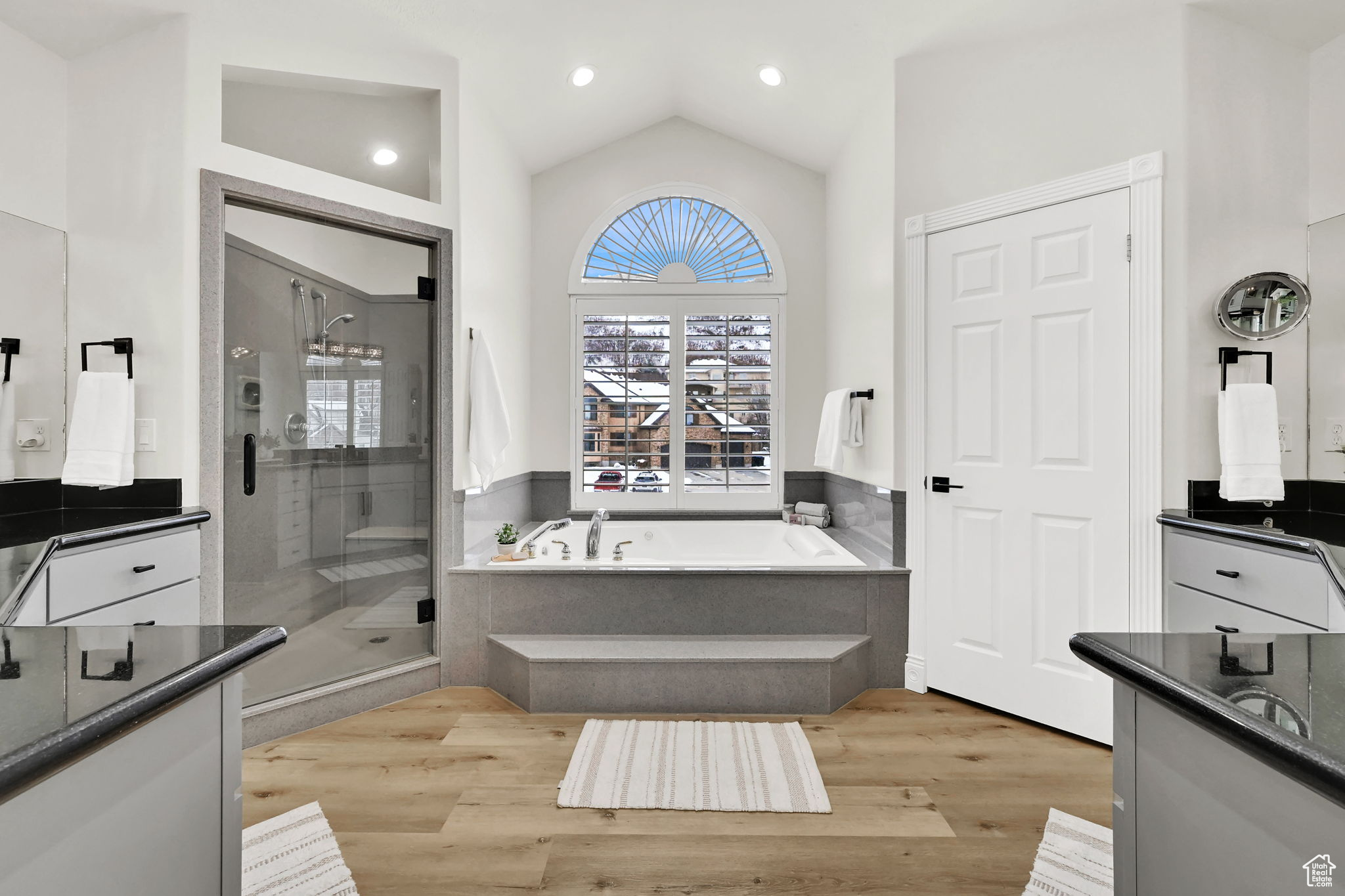 Bathroom featuring hardwood / wood-style floors, vanity, separate shower and tub, and vaulted ceiling