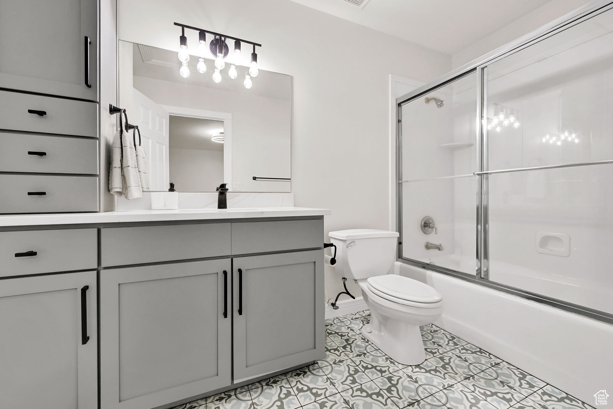 Full bathroom featuring tile patterned flooring, vanity, toilet, and combined bath / shower with glass door