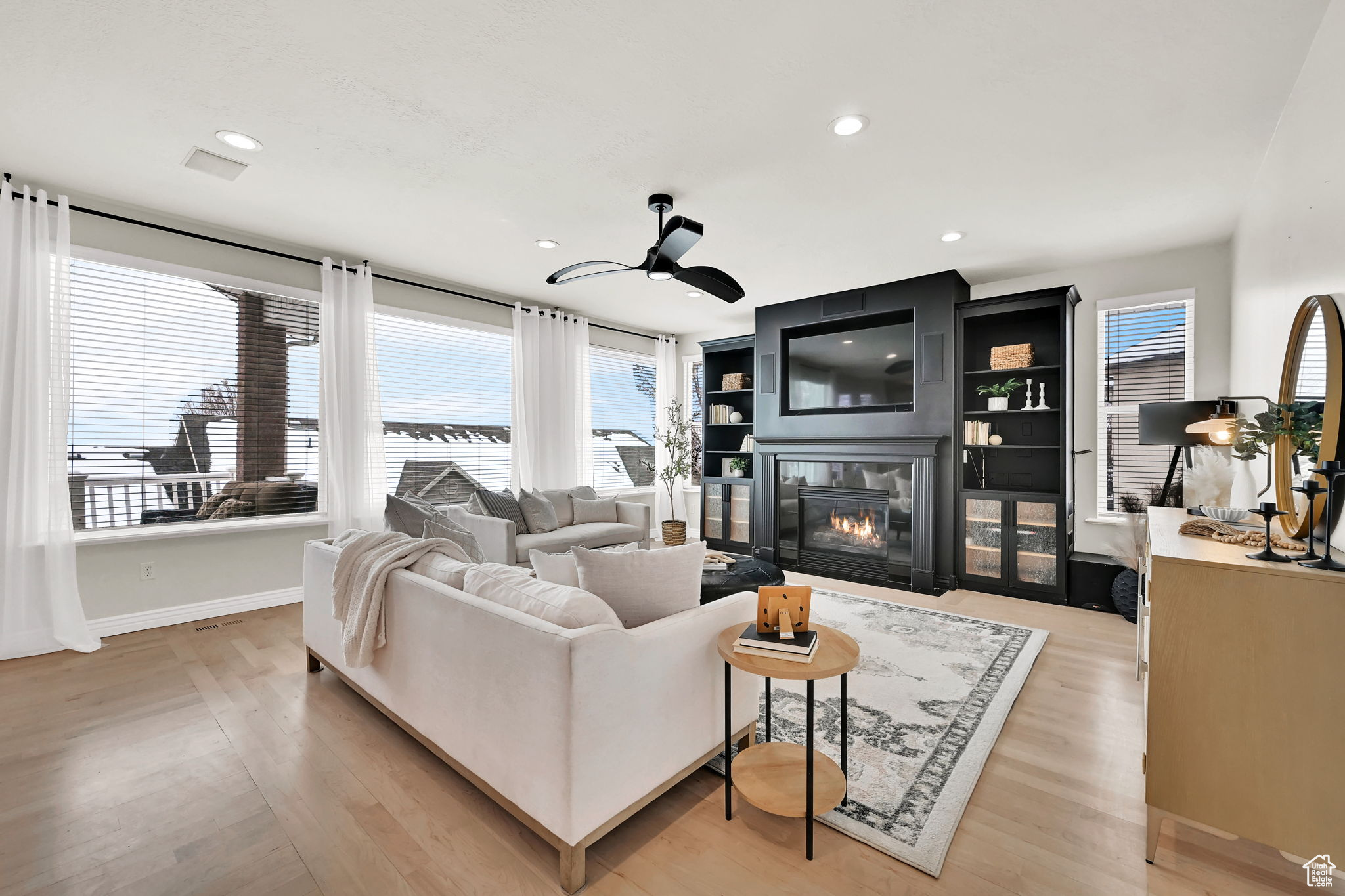 Family room featuring a wealth of natural light, a fireplace, ceiling fan, and light hardwood / wood-style flooring