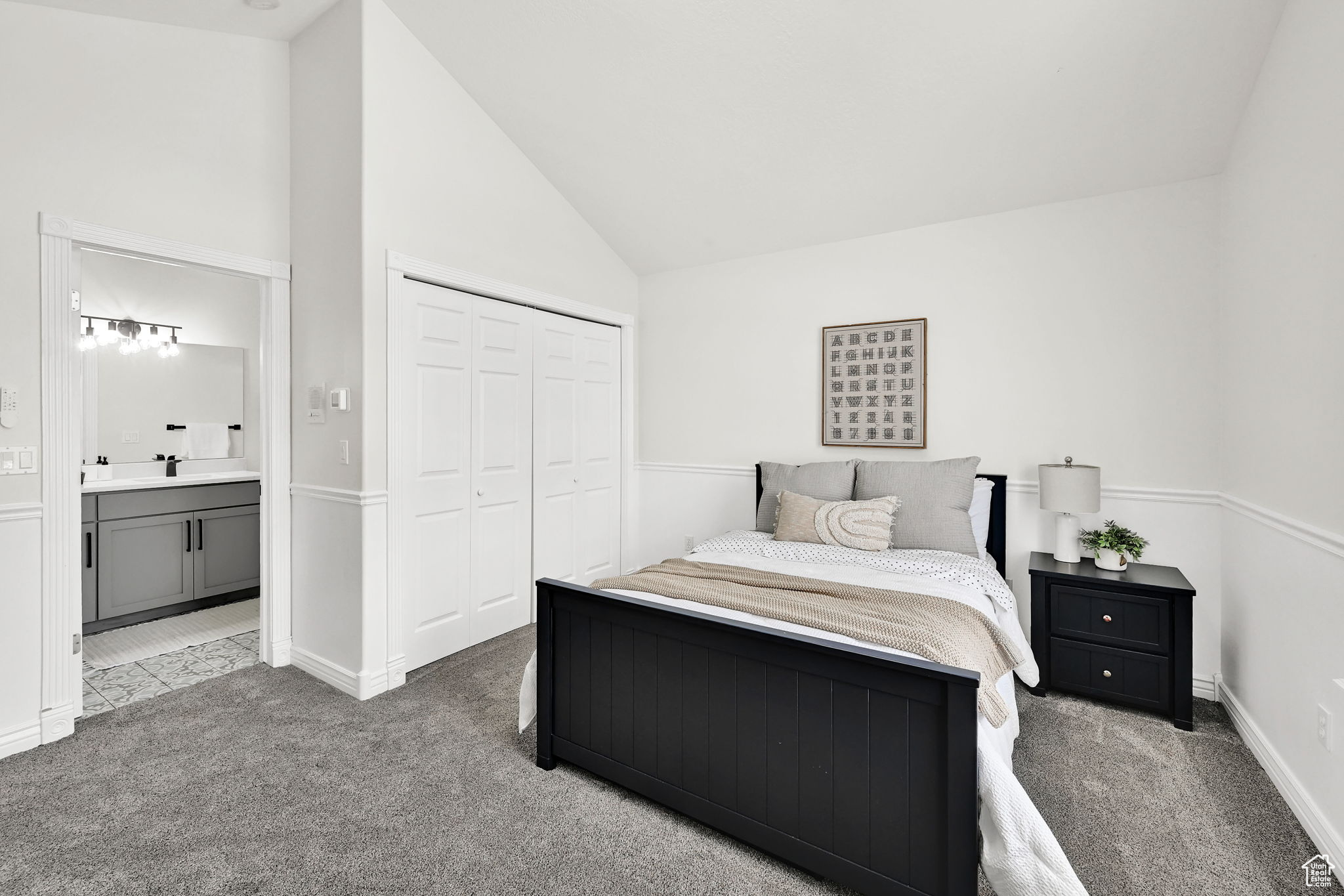 Carpeted bedroom featuring vaulted ceiling, connected bathroom, and a closet