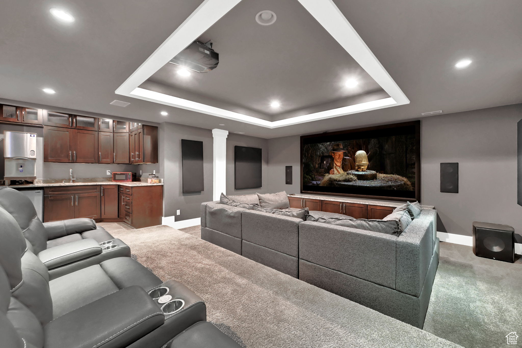 Carpeted home theater featuring a raised ceiling and wet bar