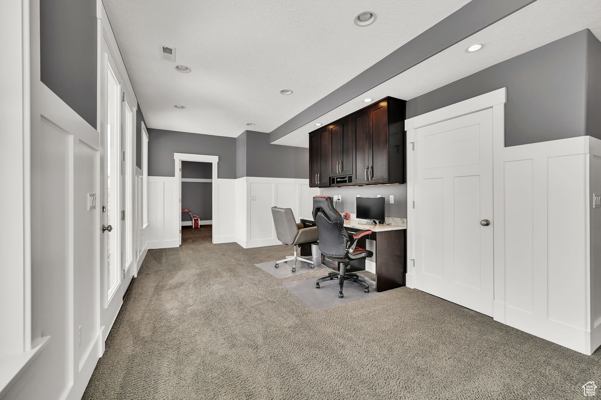 Office area with built in desk and dark carpet