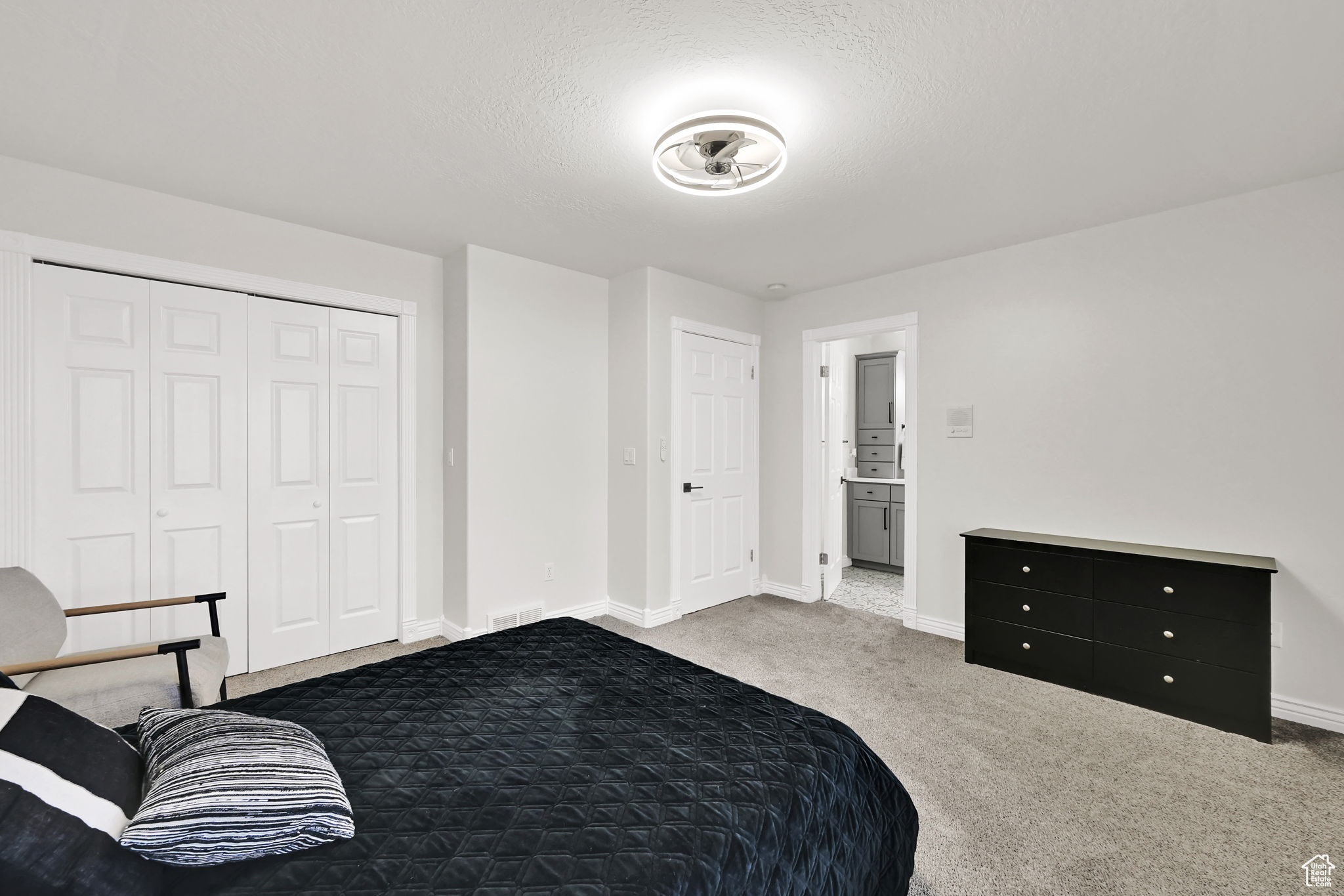 Bedroom with carpet flooring, a textured ceiling, connected bathroom, and a closet