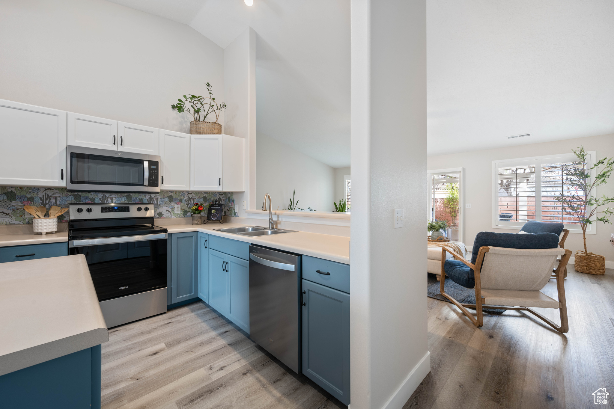 Kitchen featuring a sink, stainless steel appliances, light countertops, light wood-style floors, and blue cabinets