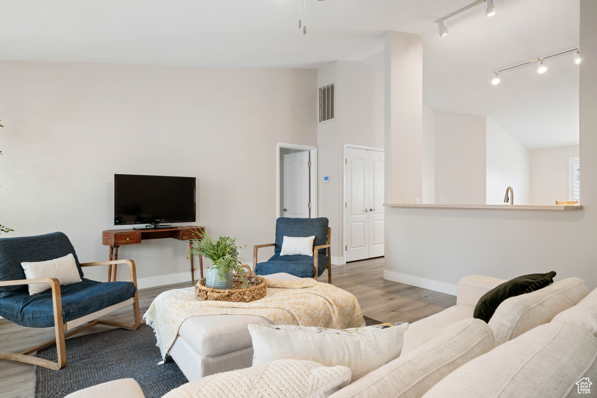 Living room featuring visible vents, lofted ceiling, baseboards, and wood finished floors