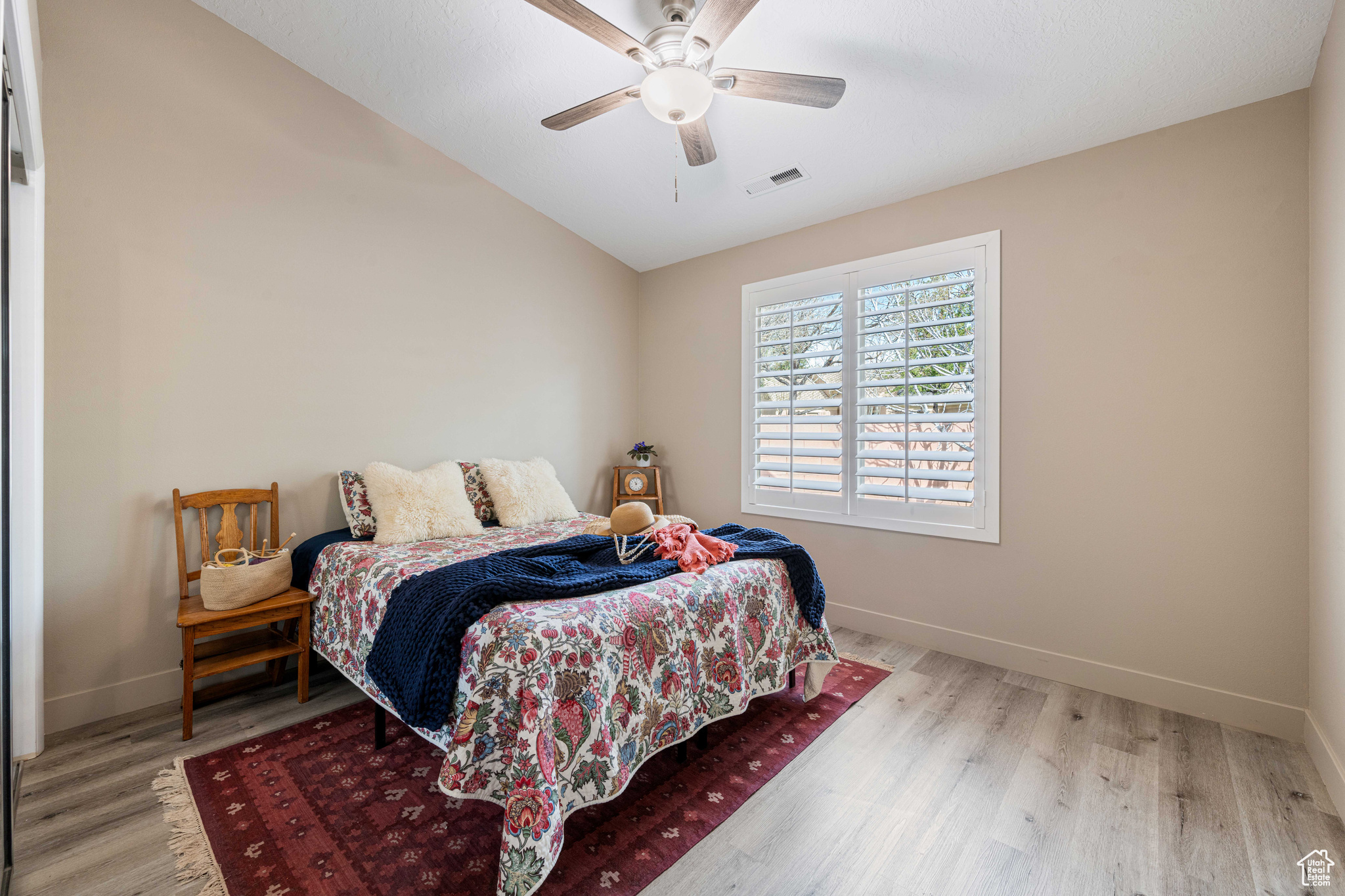 Bedroom featuring lofted ceiling, wood finished floors, visible vents, and baseboards
