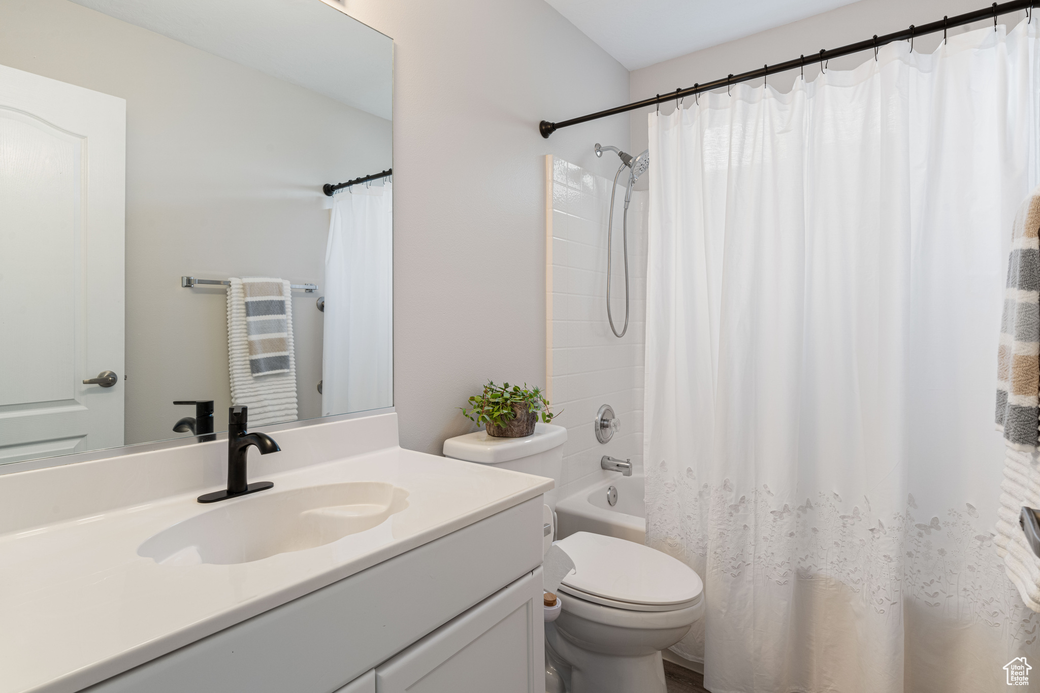 Bathroom featuring shower / tub combo with curtain, toilet, and vanity