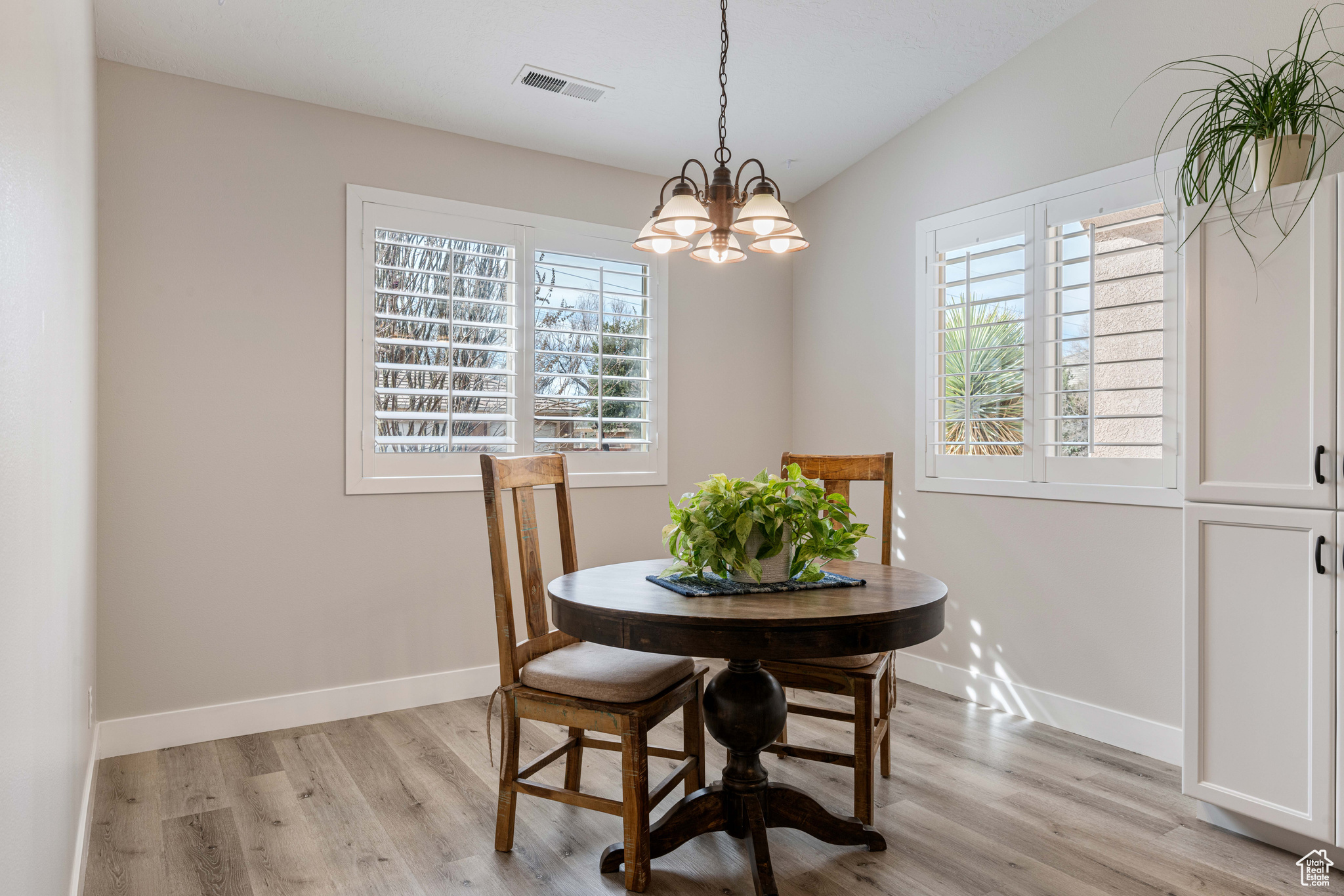 Dining room with visible vents, baseboards, light wood-style floors, and an inviting chandelier