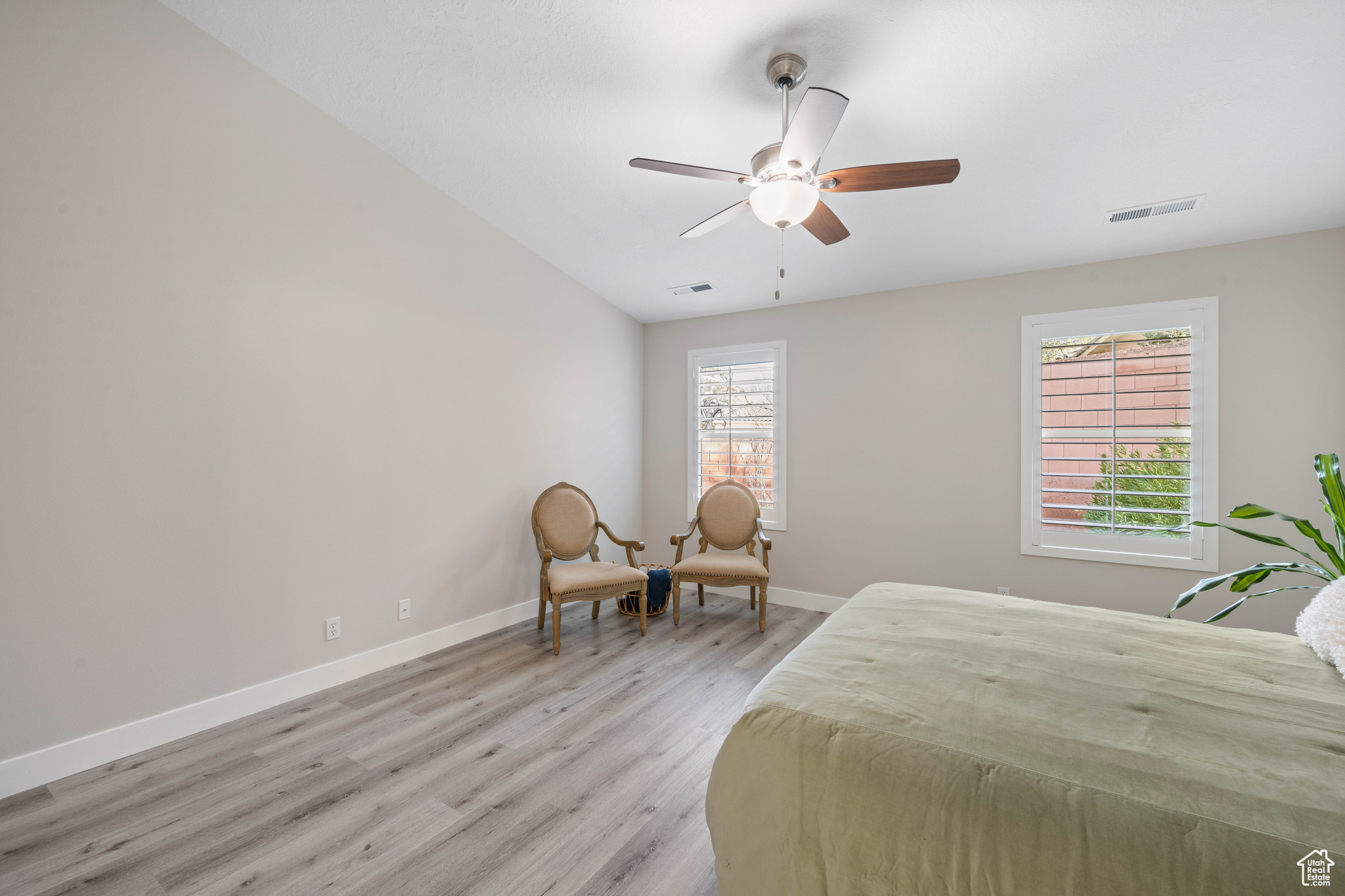 Bedroom with a ceiling fan, light wood-style floors, visible vents, and baseboards