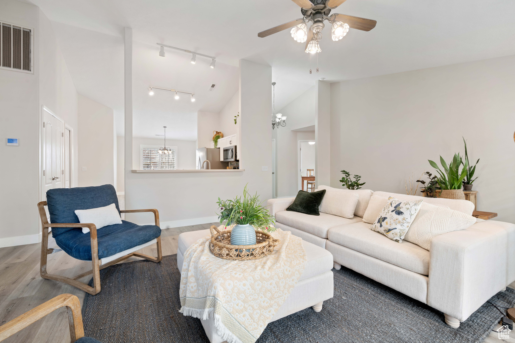 Living room with visible vents, high vaulted ceiling, baseboards, and wood finished floors