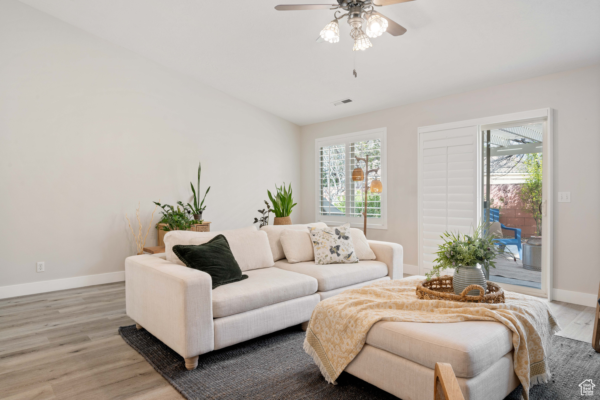 Living area featuring wood finished floors, a healthy amount of sunlight, visible vents, and baseboards