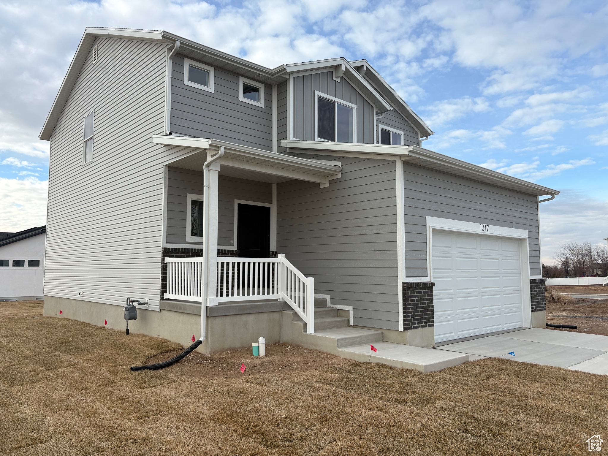 View of front facade with a front lawn, covered porch, and a garage