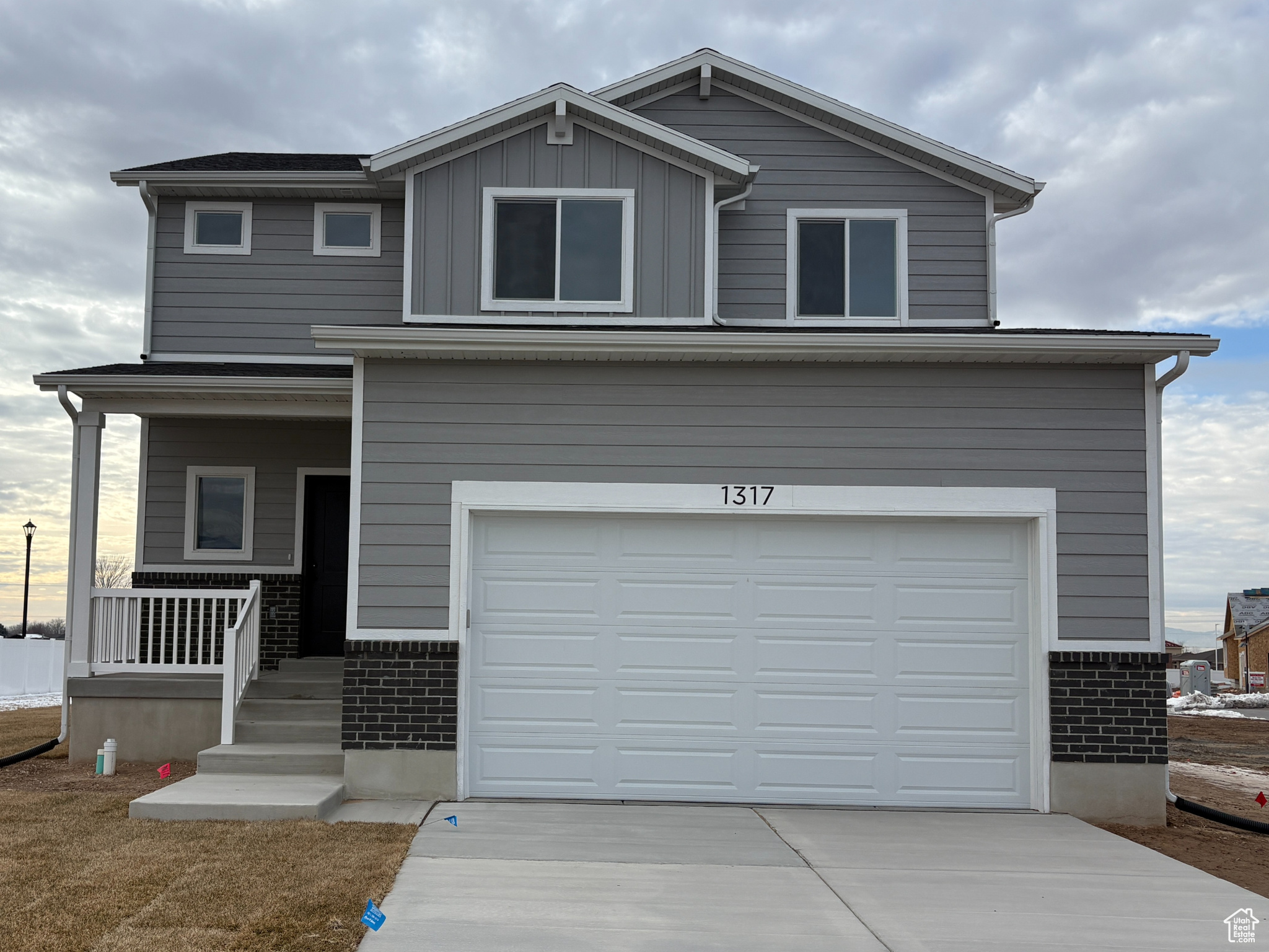 View of front facade featuring a porch, a garage, and a front lawn