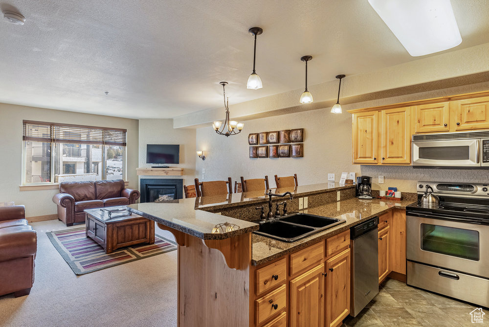 Kitchen with sink, kitchen peninsula, decorative light fixtures, a breakfast bar, and appliances with stainless steel finishes