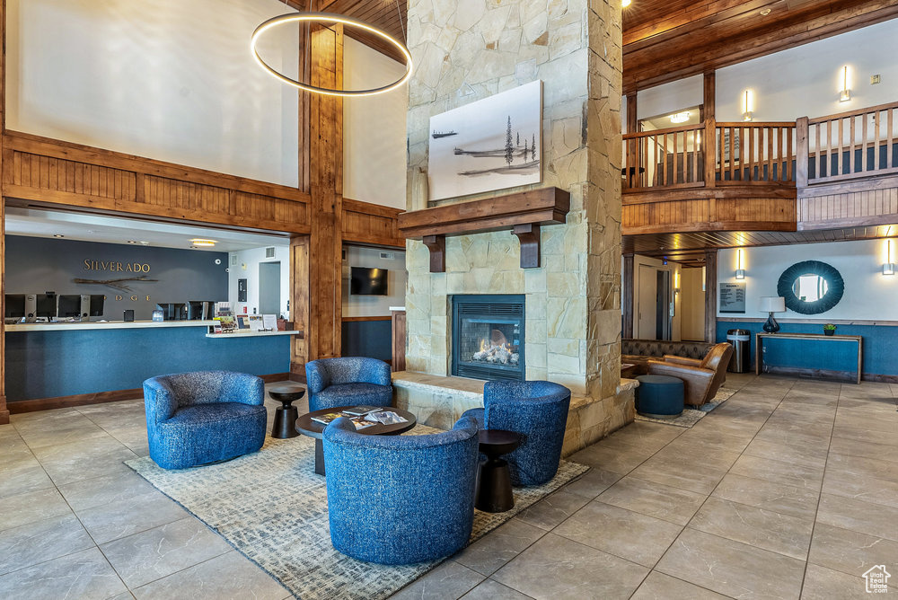 Living room featuring light tile patterned flooring, a stone fireplace, and a high ceiling