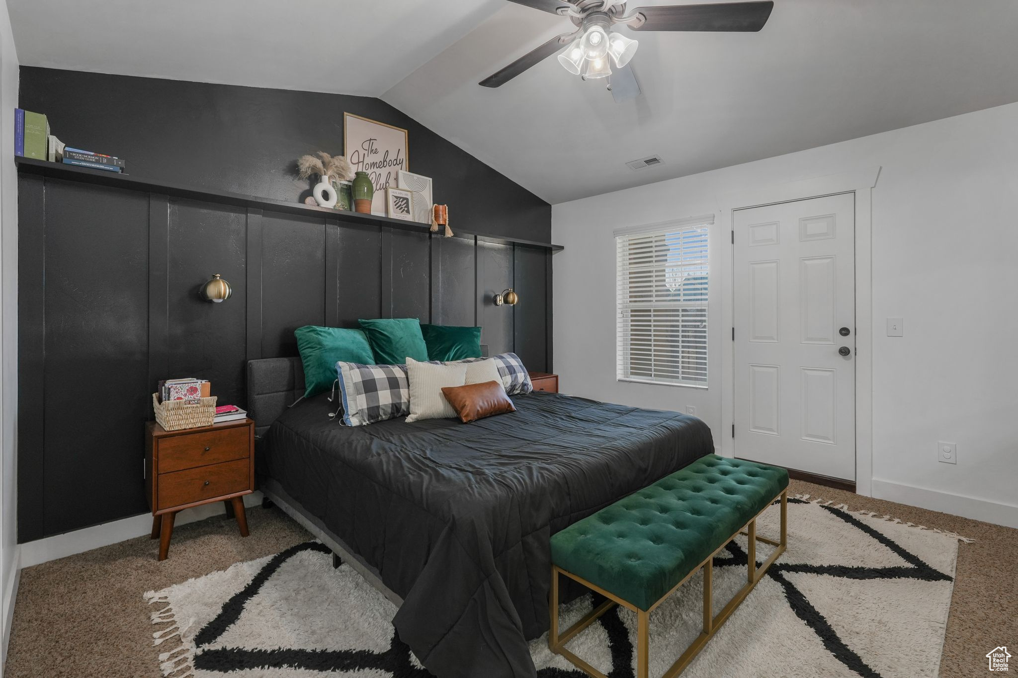 Bedroom featuring light carpet, vaulted ceiling, and ceiling fan.  Door goes to a large deck.