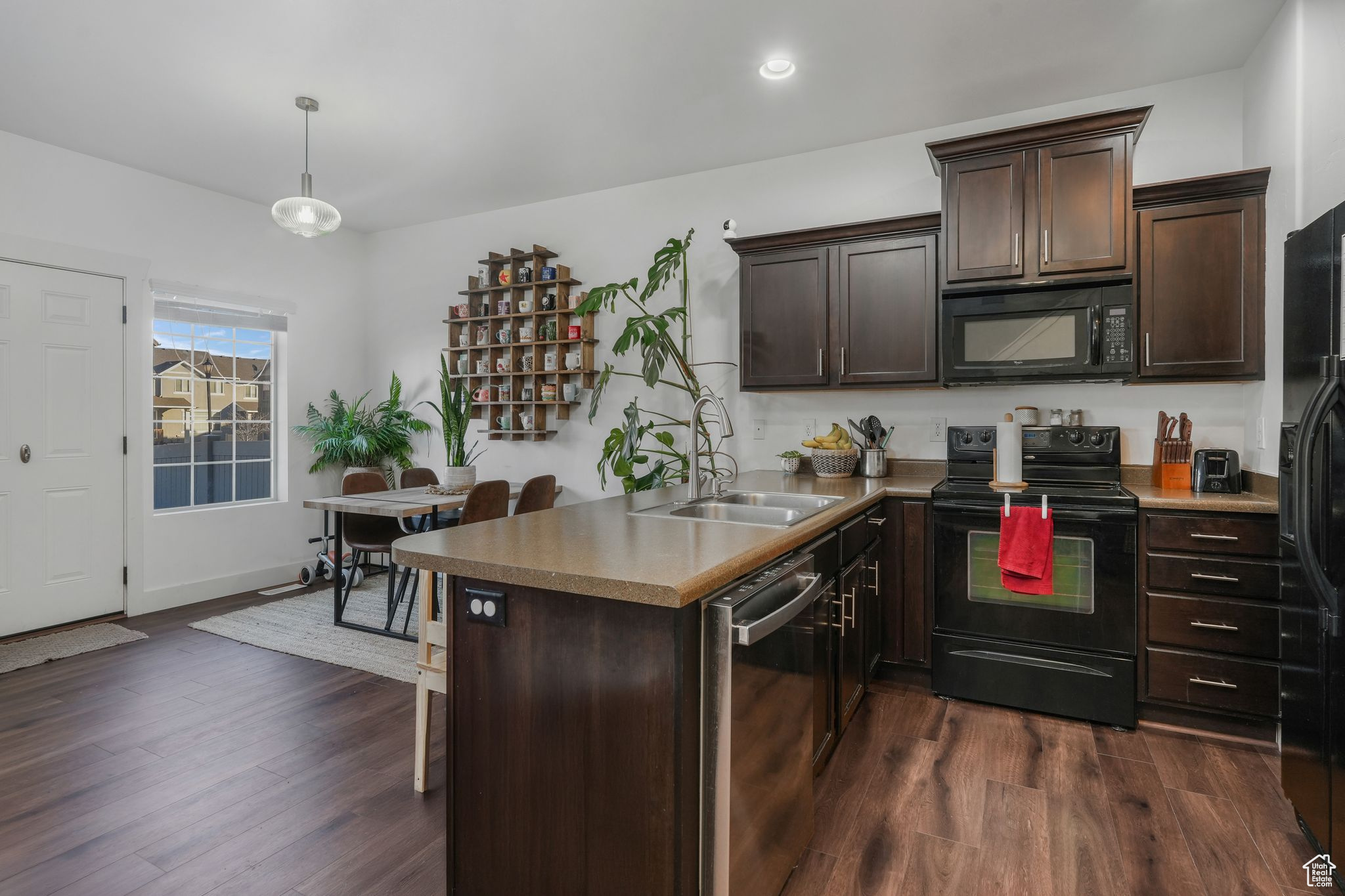 Kitchen featuring dark brown cabinets, sink, black appliances, and decorative light fixtures
