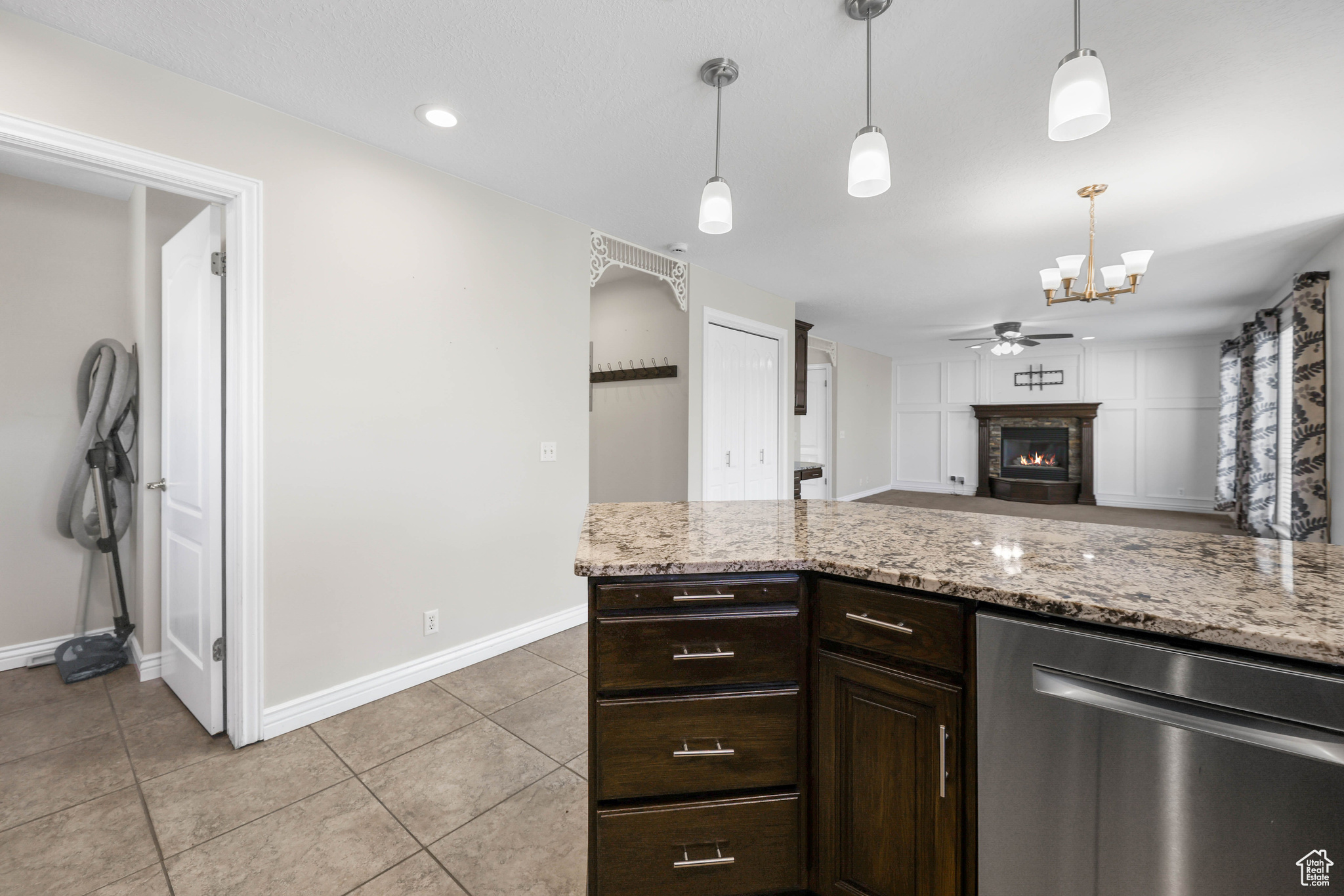 Kitchen featuring light stone counters, dark brown cabinets, ceiling fan, pendant lighting, and dishwasher