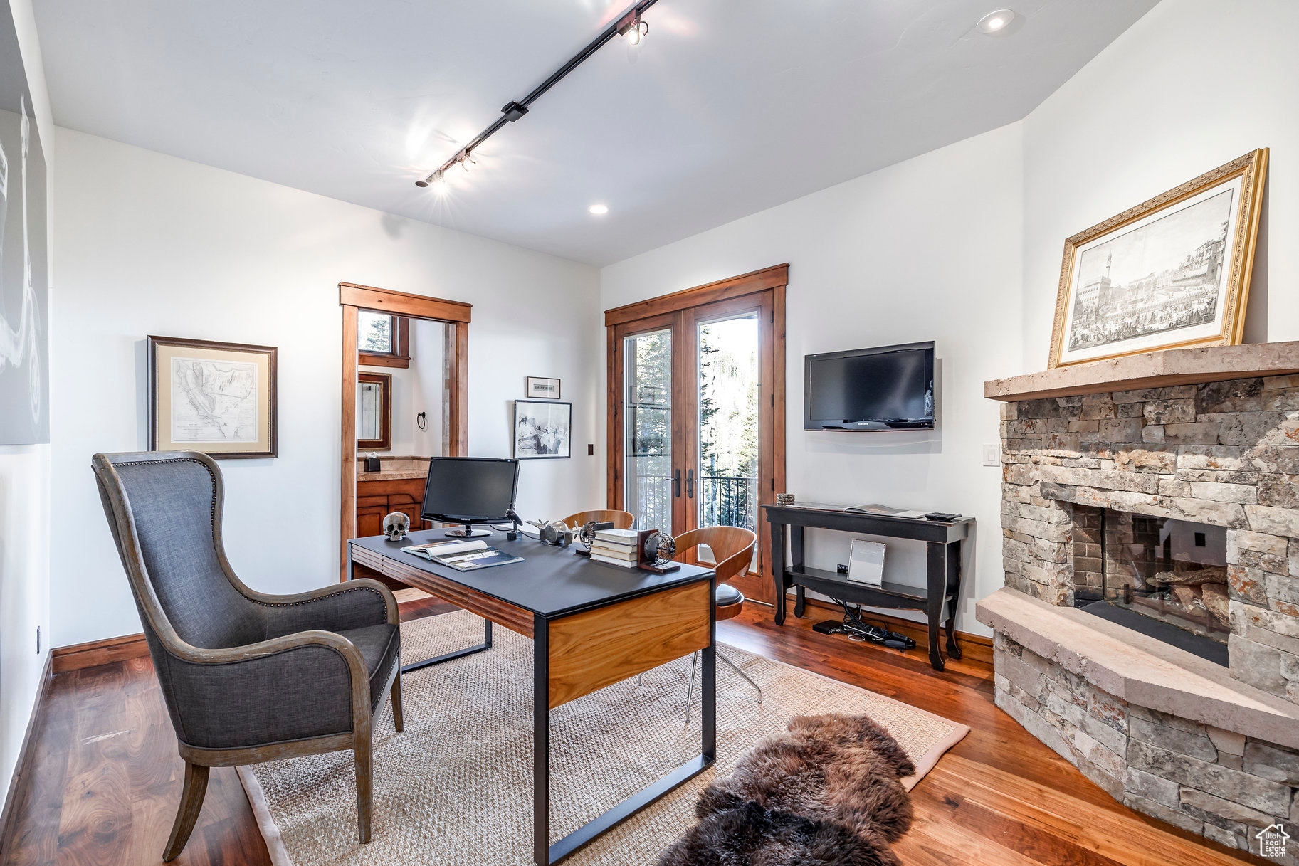 Office area with a stone fireplace, track lighting, and hardwood / wood-style flooring