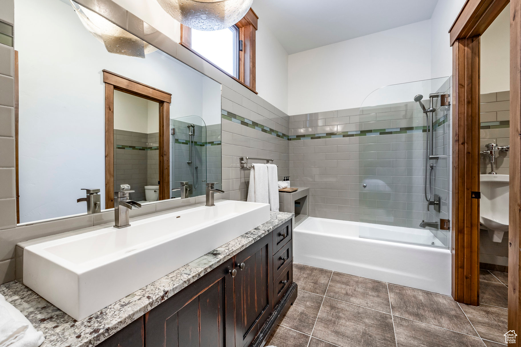 Full bathroom featuring tile patterned floors, toilet, vanity, tile walls, and tiled shower / bath
