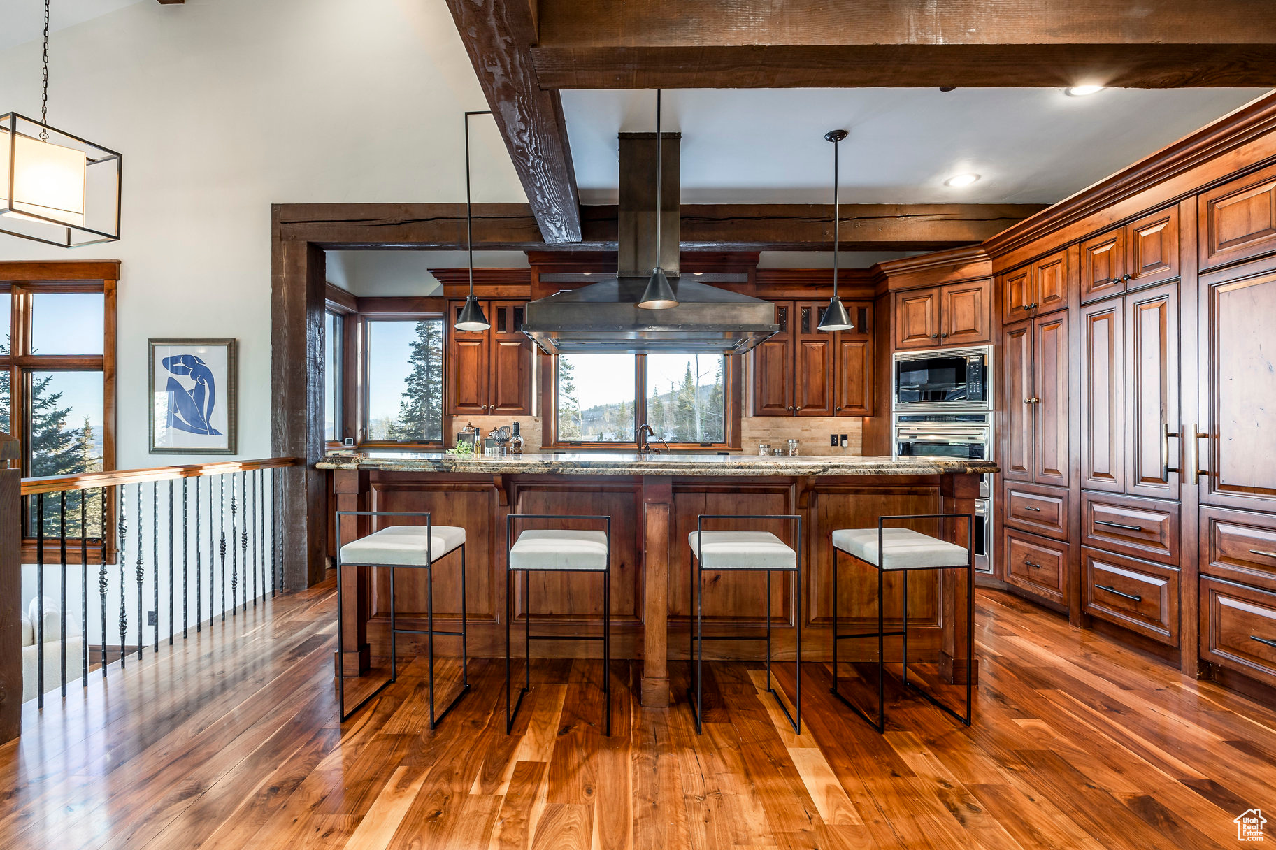 Kitchen featuring a kitchen breakfast bar, light stone countertops, stainless steel microwave, and hanging light fixtures