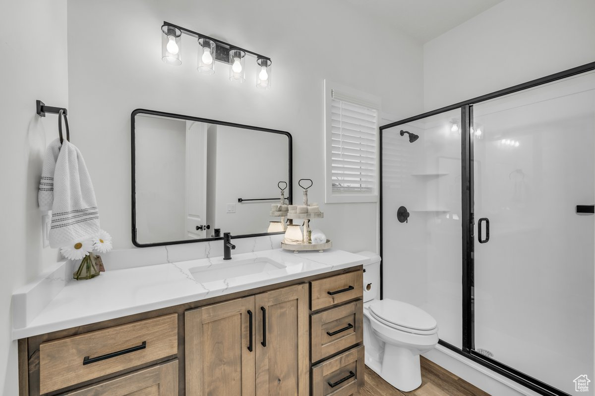 Bathroom featuring hardwood / wood-style floors, vanity, toilet, and walk in shower