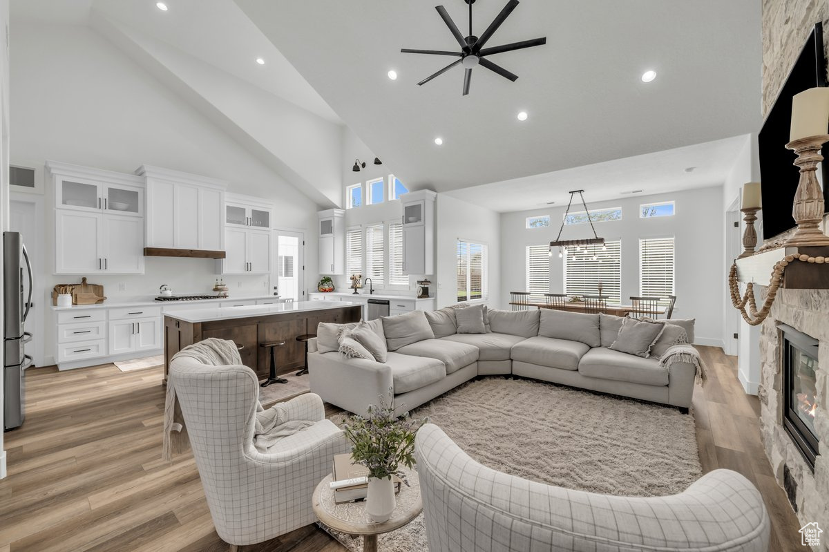 Living room featuring ceiling fan, light hardwood / wood-style floors, a fireplace, and high vaulted ceiling