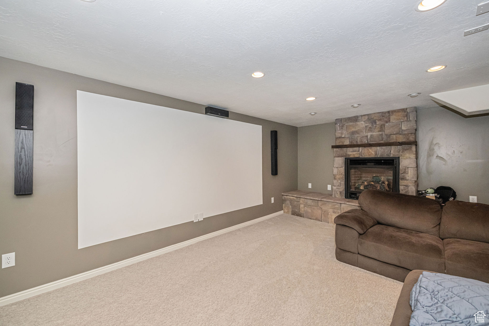 Cinema room with carpet, a fireplace, and a textured ceiling