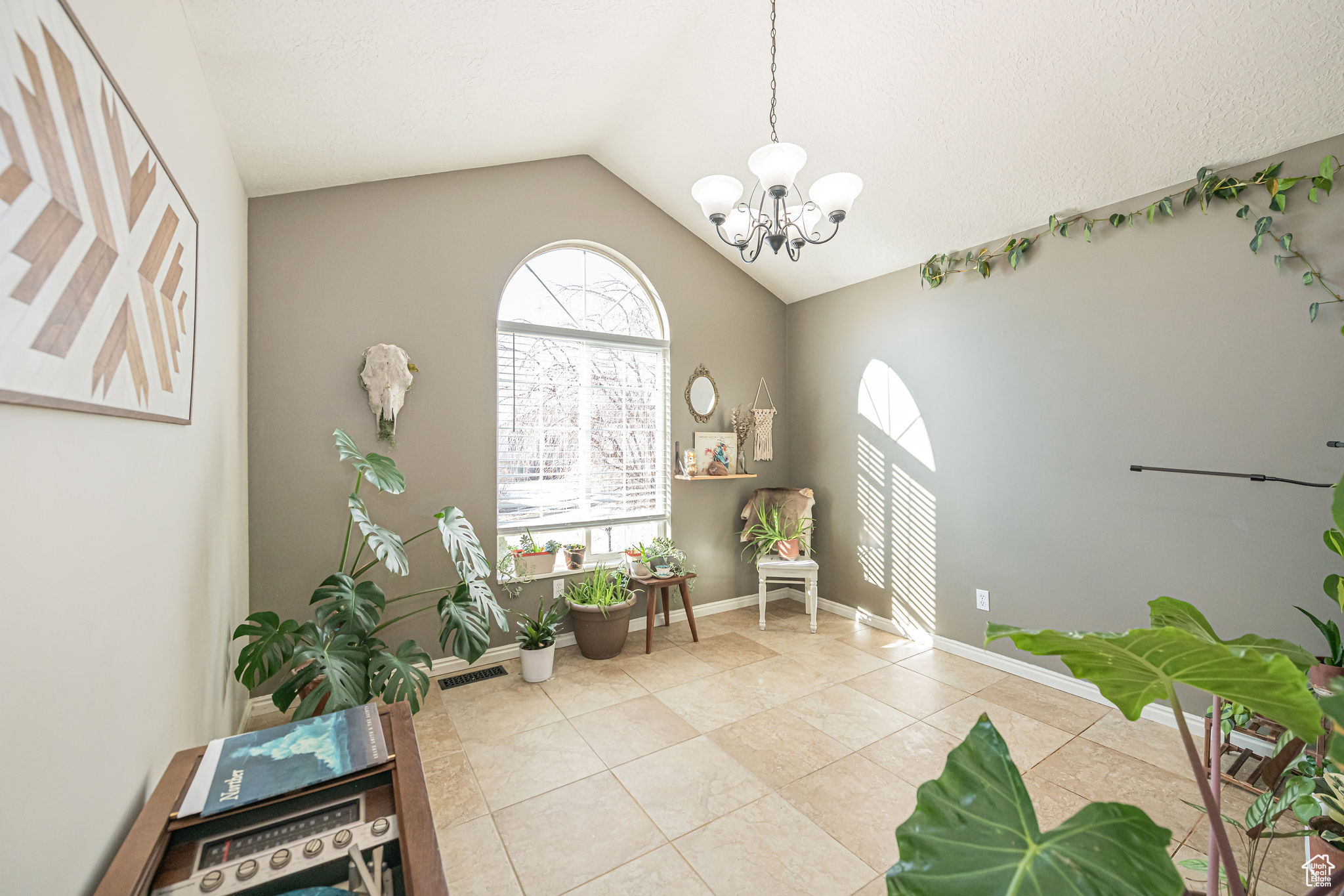 Sitting room with an inviting chandelier, light tile patterned floors, and vaulted ceiling
