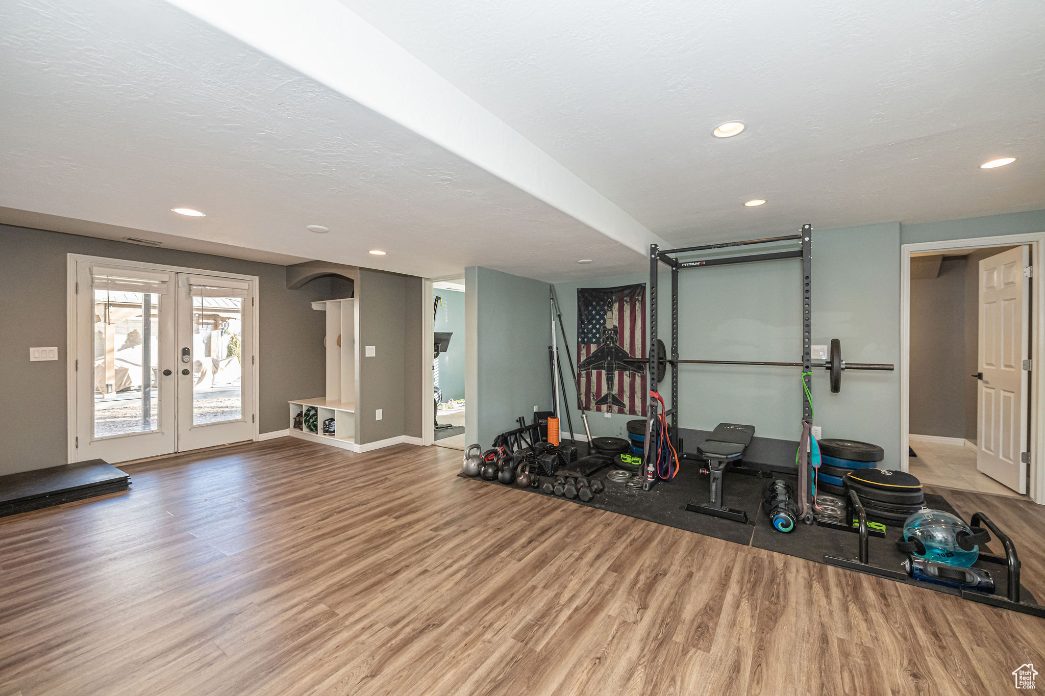 Exercise room with french doors, wood-type flooring, and a textured ceiling