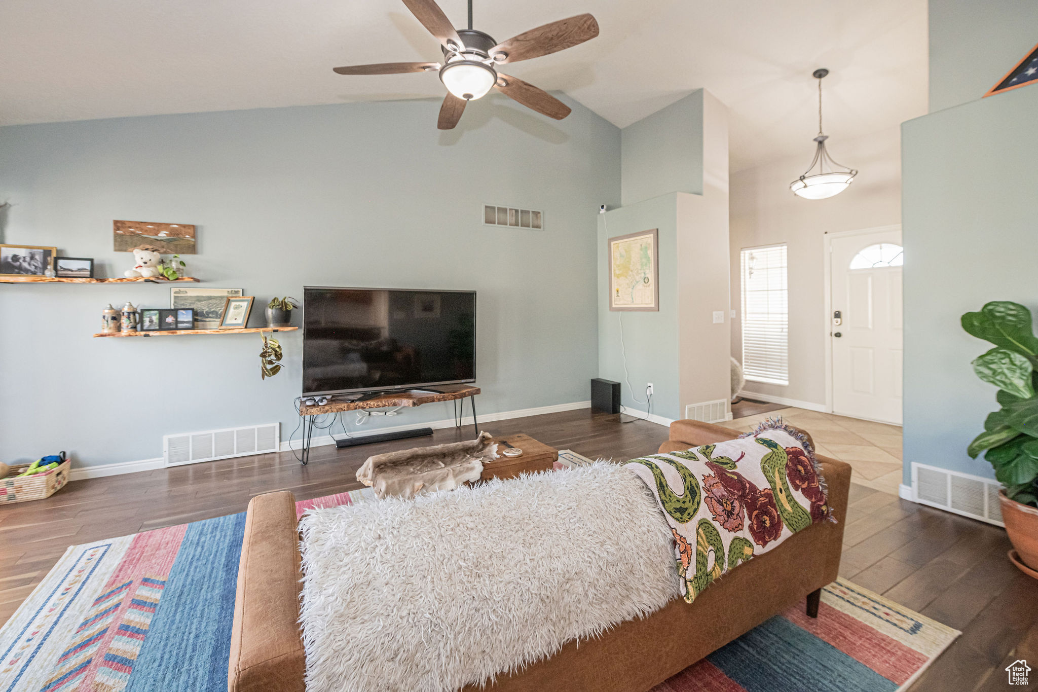Living room with ceiling fan, high vaulted ceiling, and dark wood-type flooring