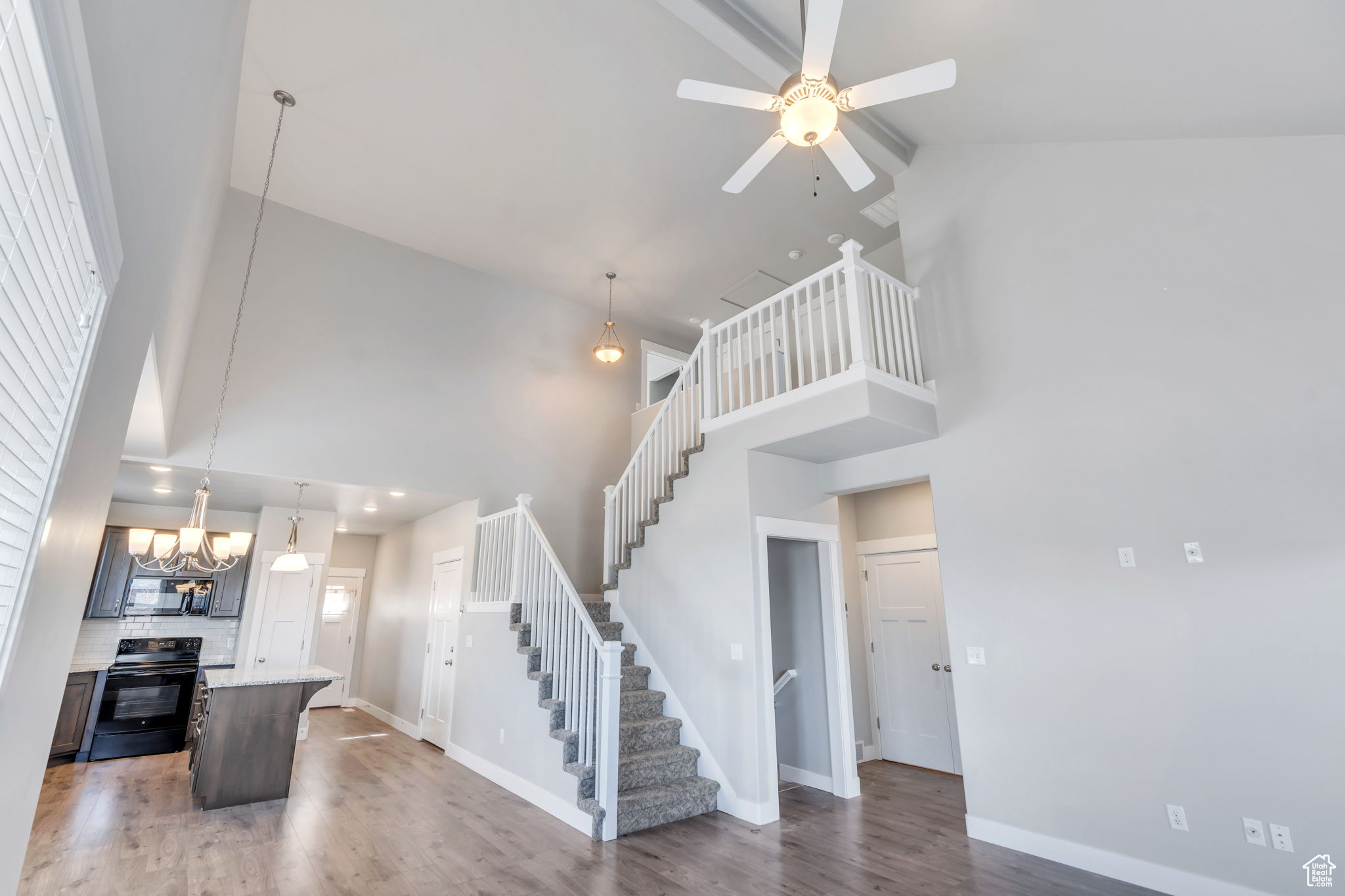 Kitchen featuring a center island, high vaulted ceiling, black appliances, and ceiling fan with notable chandelier