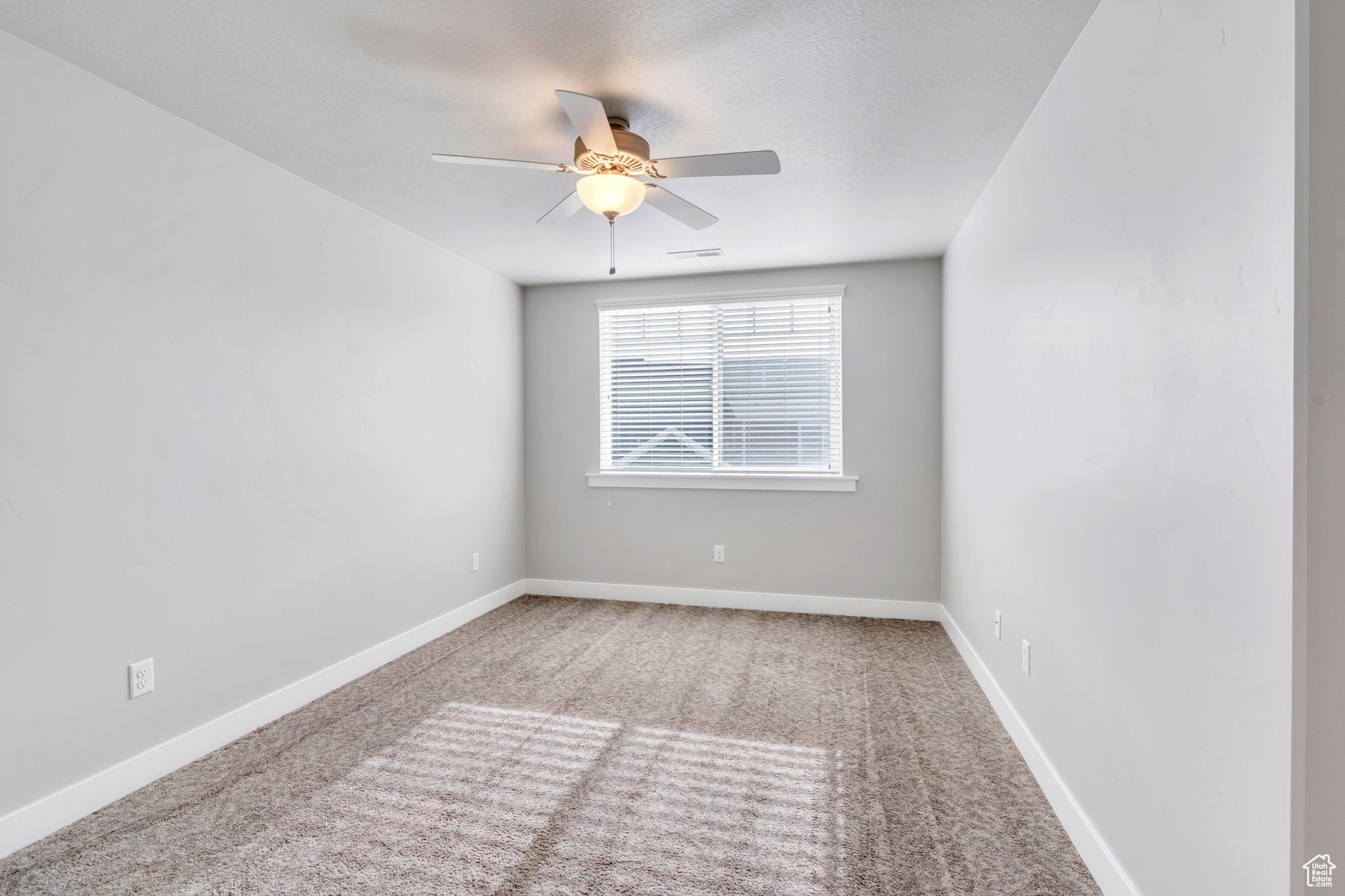 Carpeted empty room with ceiling fan