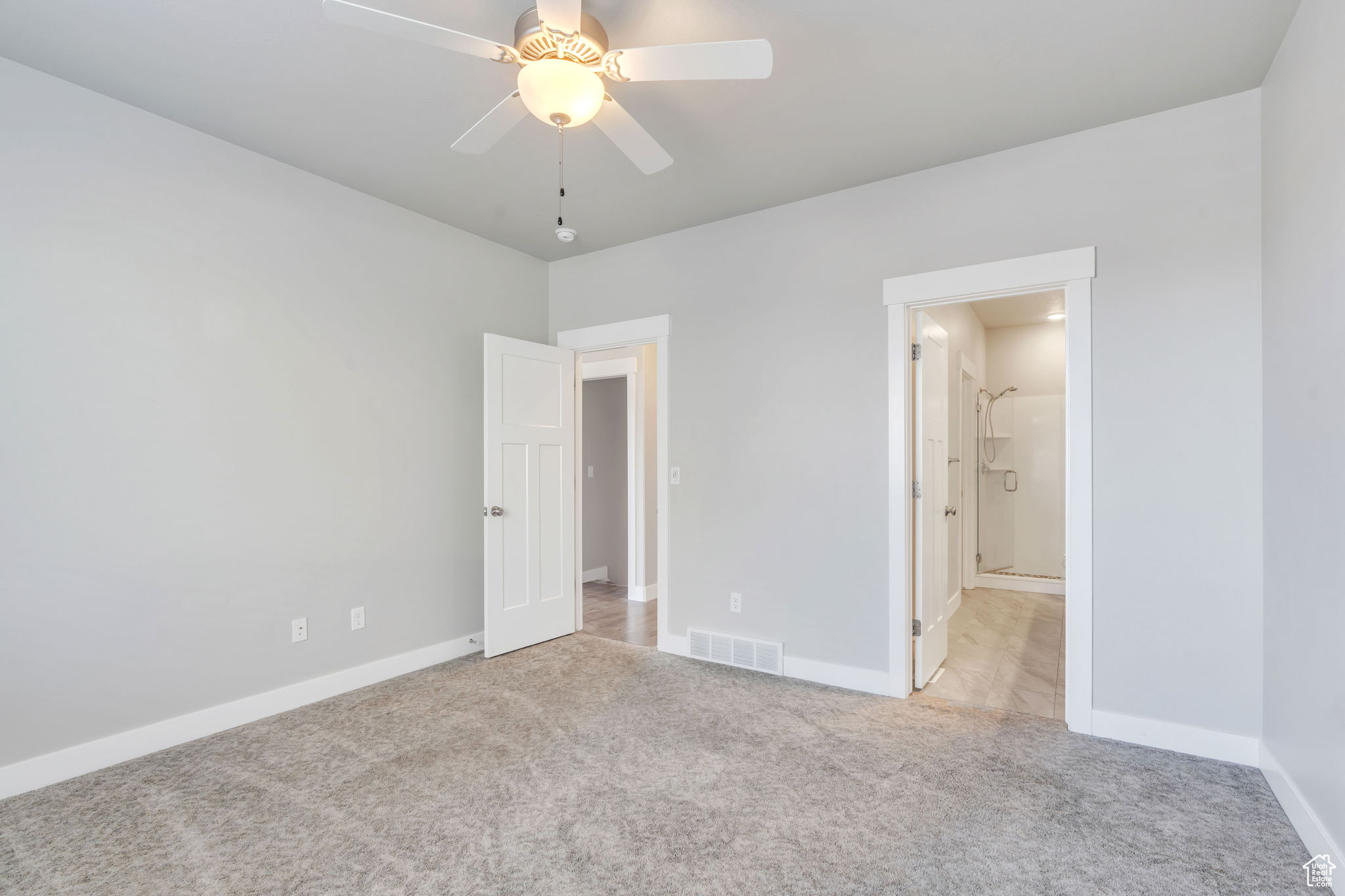 Unfurnished bedroom with ceiling fan and light colored carpet