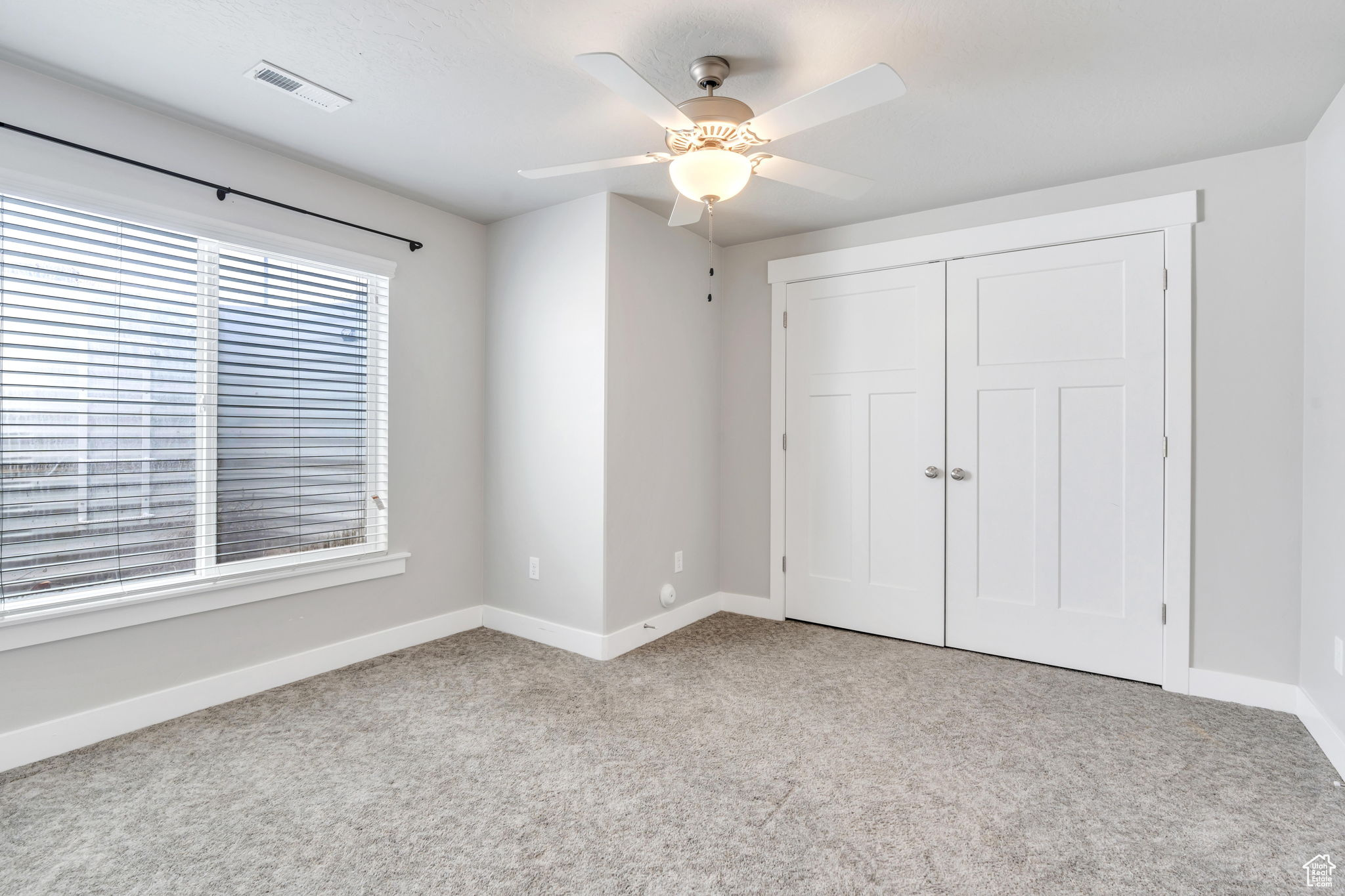 Unfurnished bedroom featuring a closet, ceiling fan, and light colored carpet