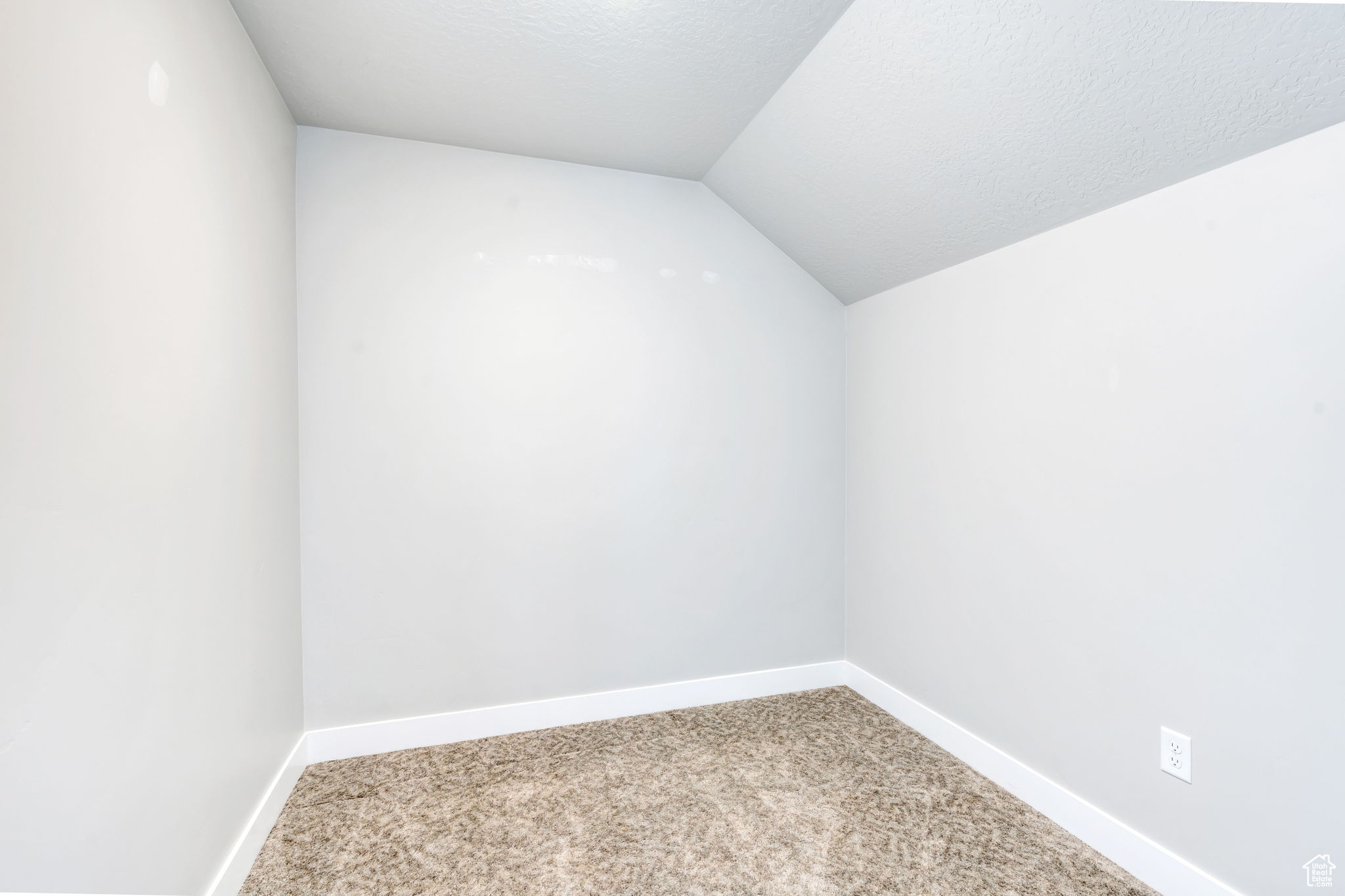 Carpeted empty room featuring a textured ceiling and lofted ceiling